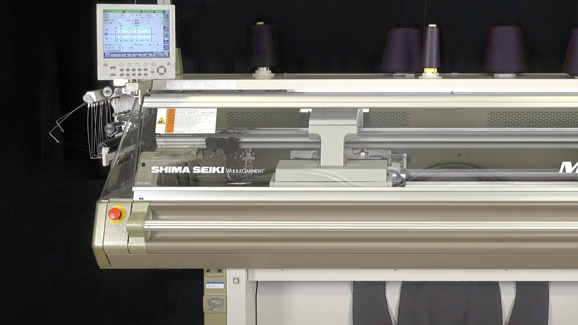 A large silver and grey knitting machine with an assortment of navy blue spools of thread on top.