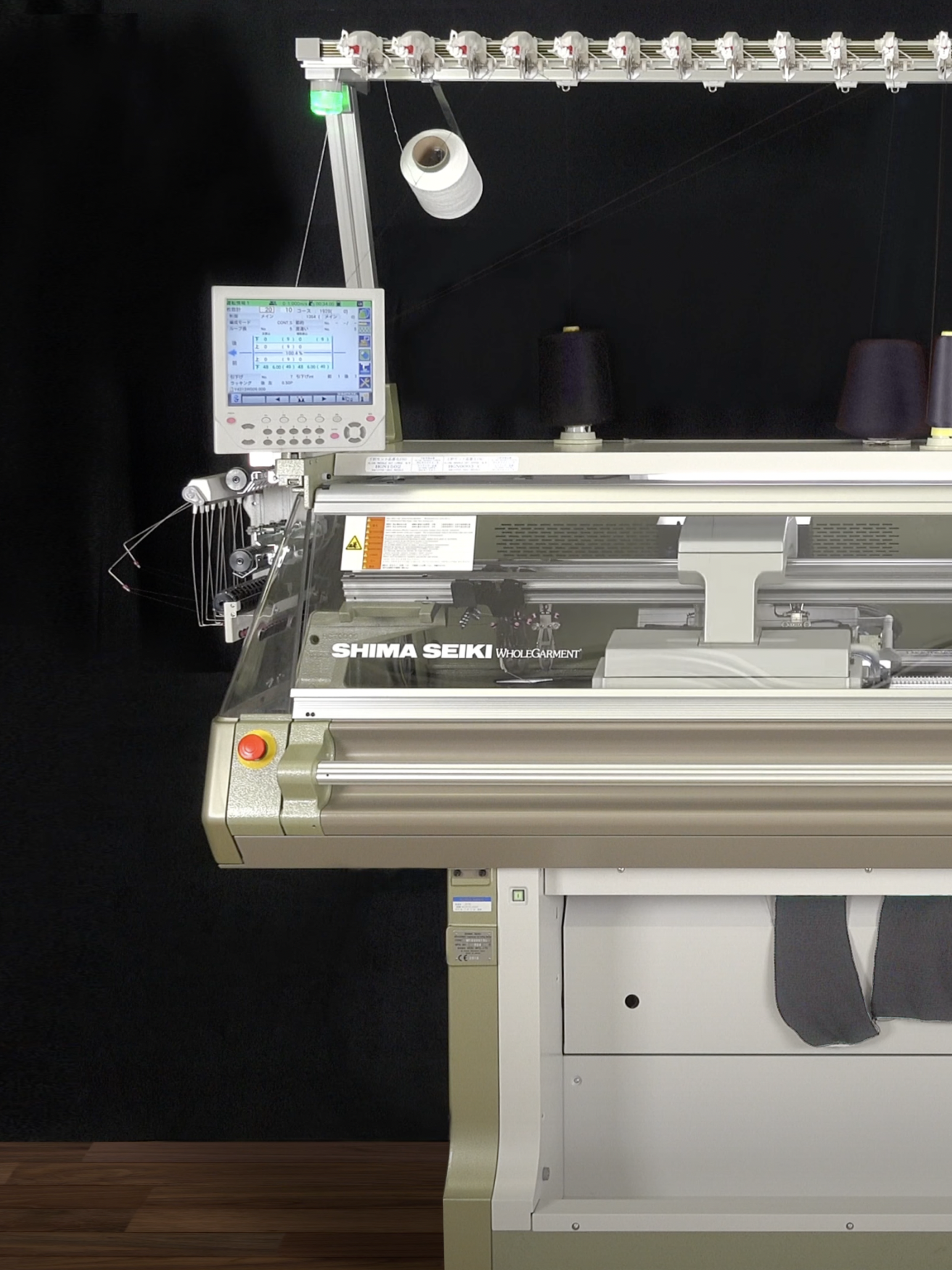A large silver and grey knitting machine with an assortment of navy blue spools of thread on top.