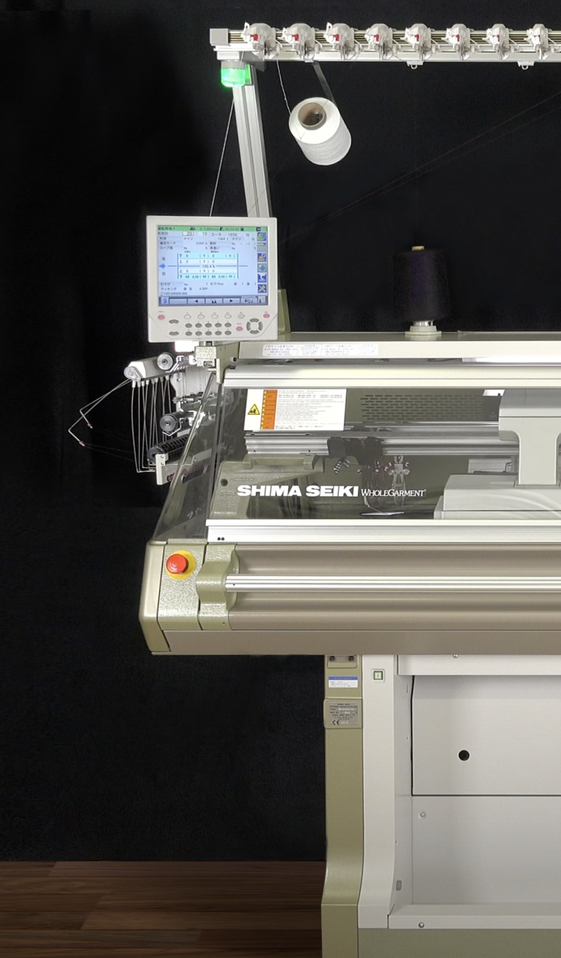 A large silver and grey knitting machine with an assortment of navy blue spools of thread on top.