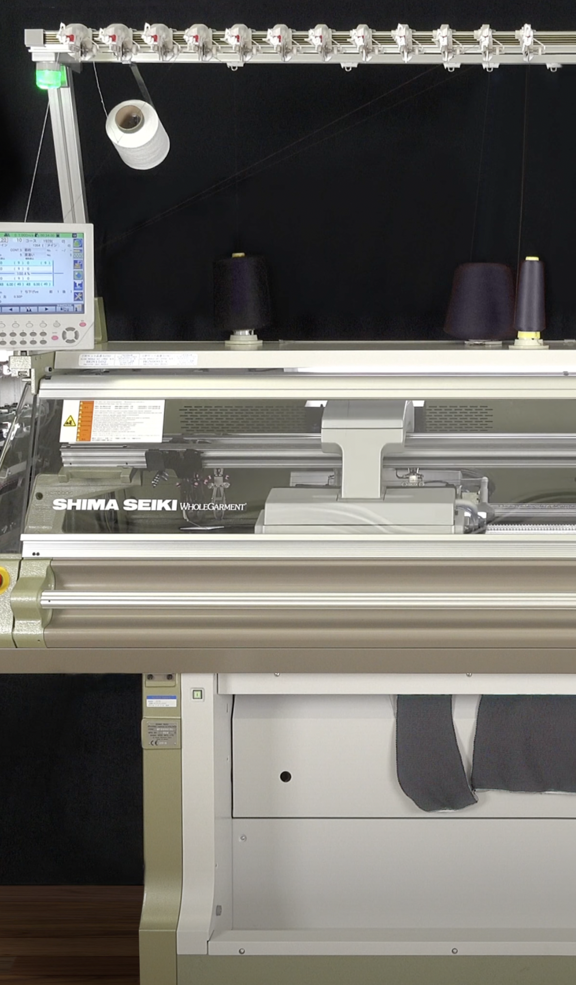 A large silver and grey knitting machine with an assortment of navy blue spools of thread on top.