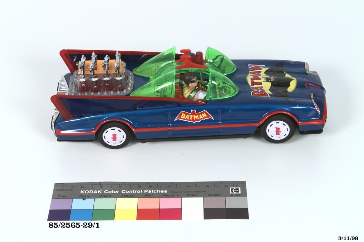 Blue toy 'Batmobile' car with green bubble windscreens, rear-mounted engine and bat-shaped logo on the door