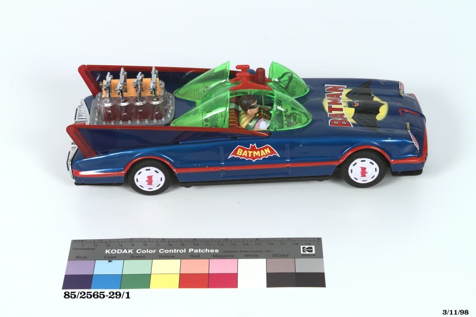 Blue toy 'Batmobile' car with green bubble windscreens, rear-mounted engine and bat-shaped logo on the door