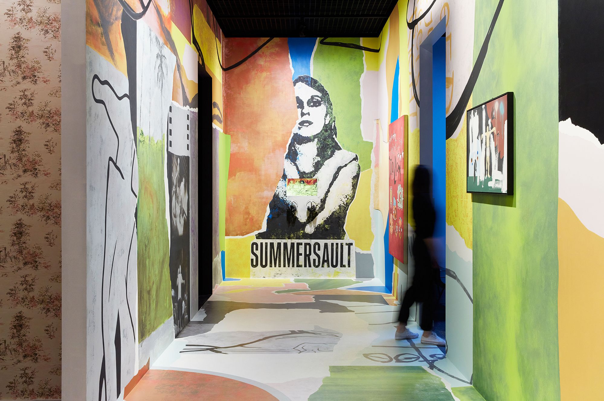 A wide corridor plastered in bright colours and music posters.