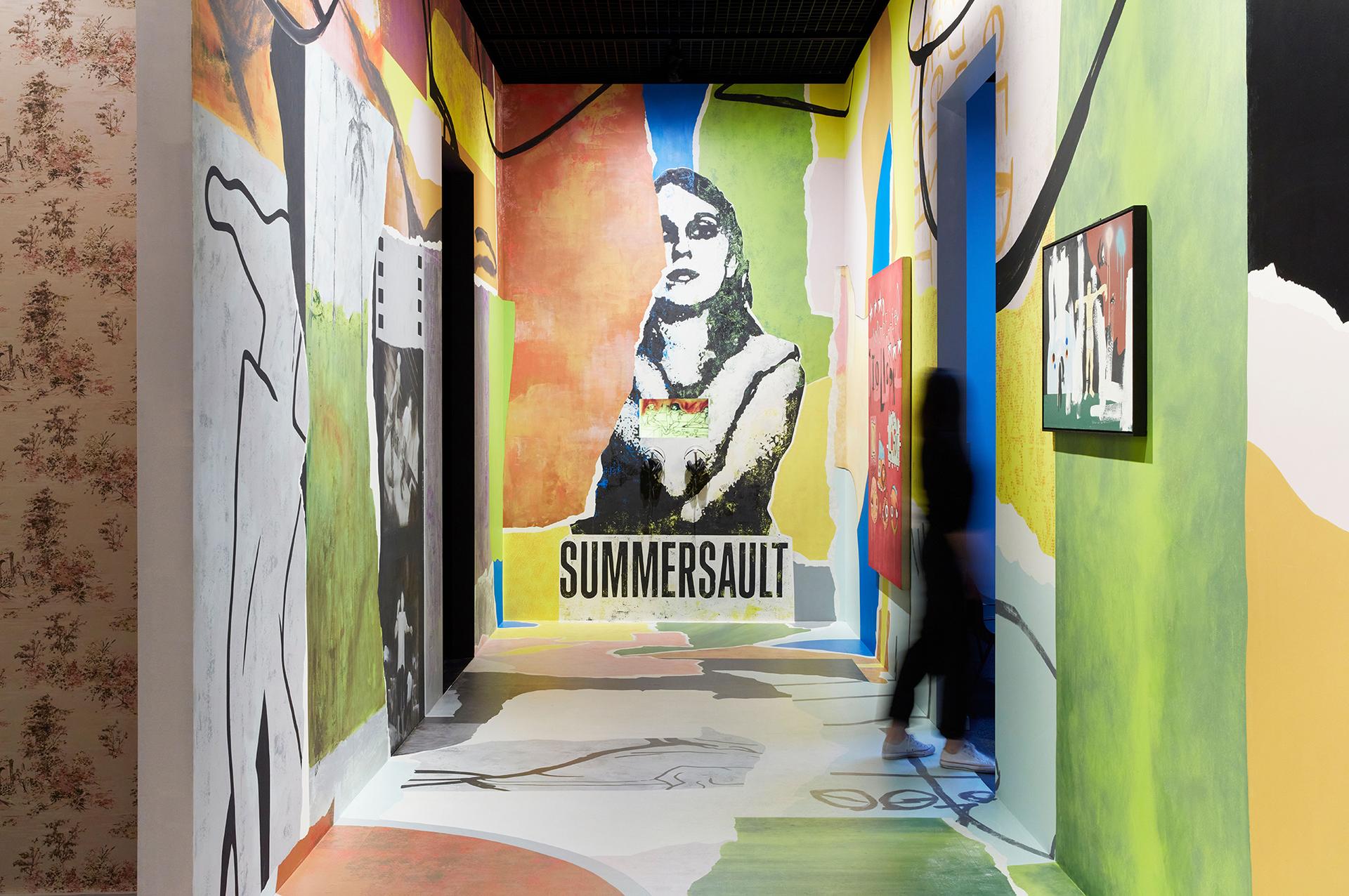 A wide corridor plastered in bright colours and music posters.