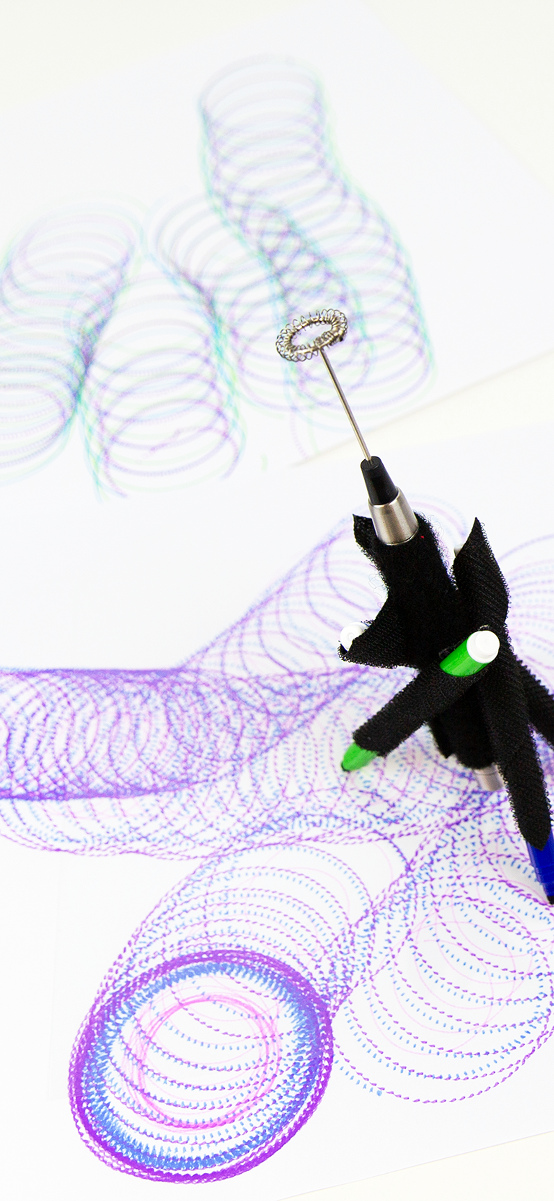 A series of spirograph drawings in blue and purple and a DrawBot device.