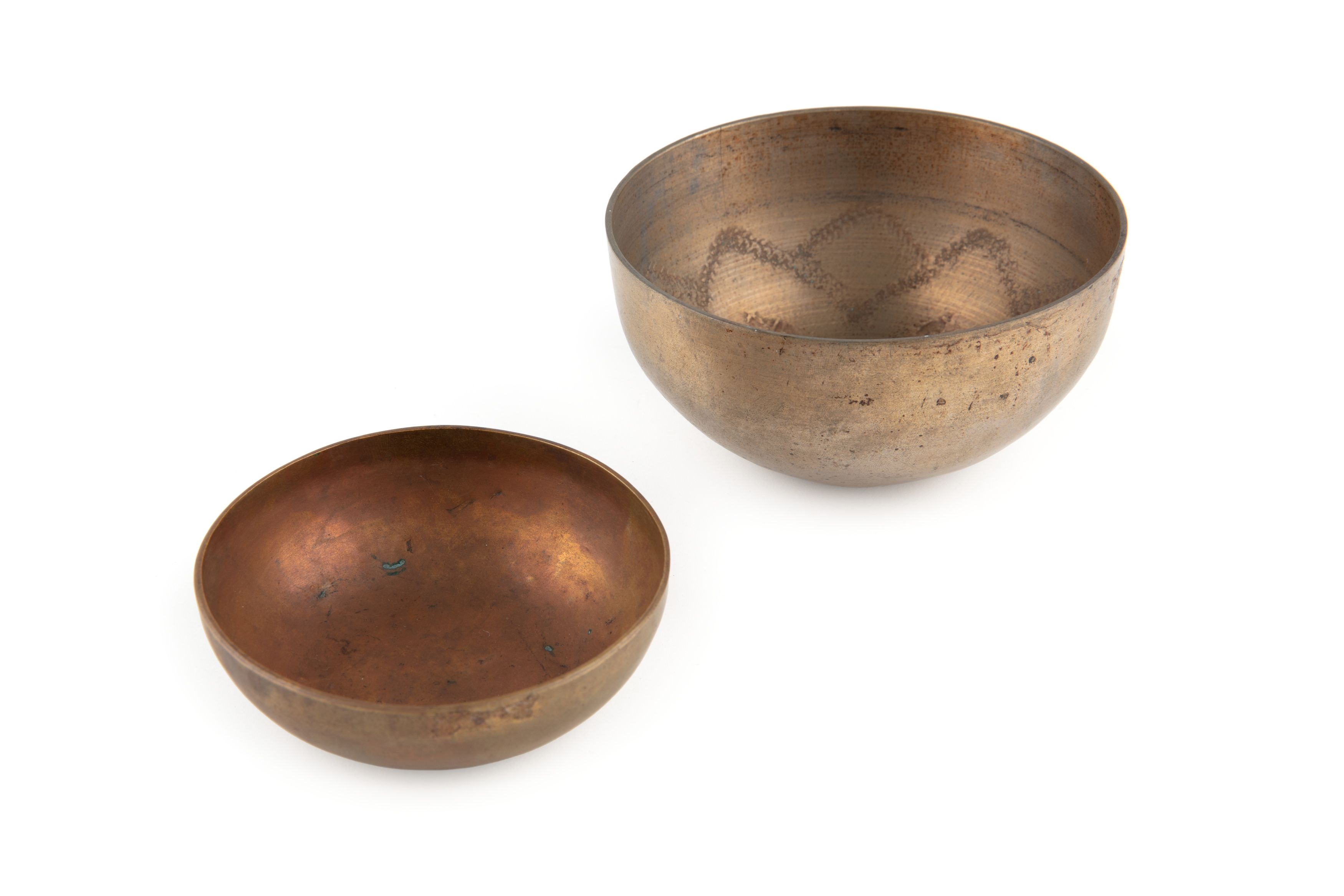 Two bowl-shaped gong parts, made of brass and tombac that have been lathe turned and are hemispherical in shape with a flower petal design in interior.