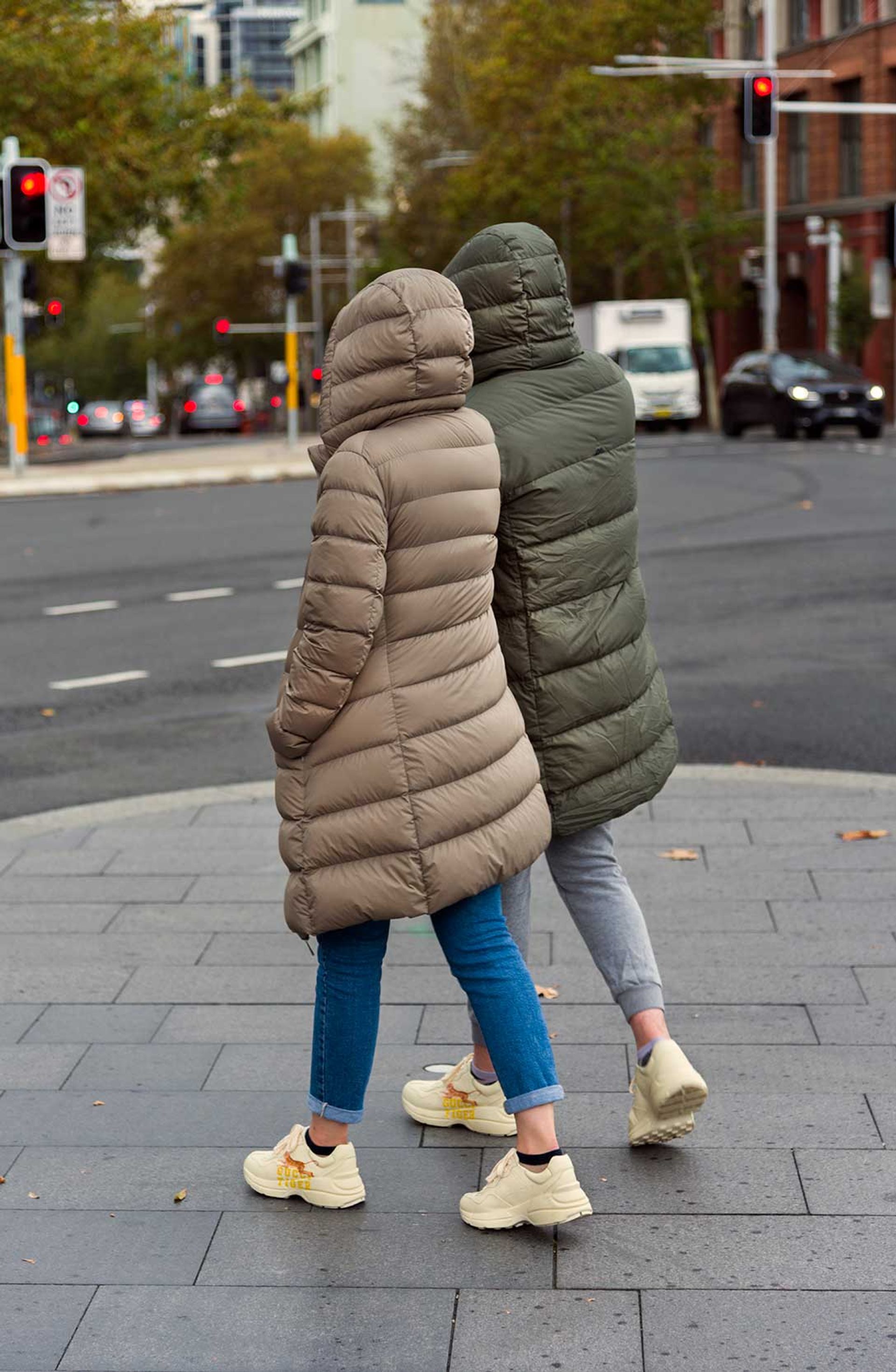 Two figures in matching puffer jackets walk side by side.