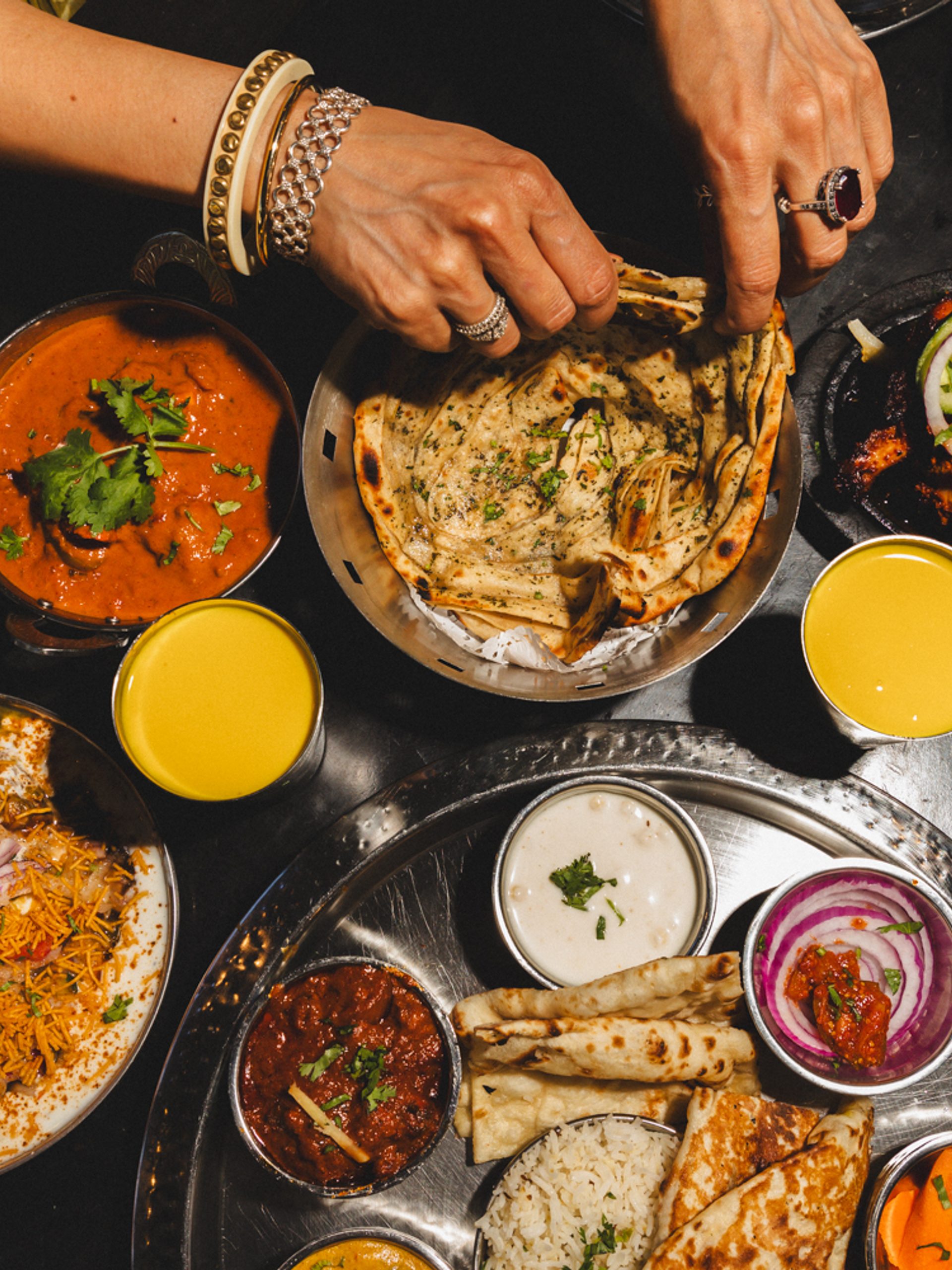 Hands reaching from a feast of food.