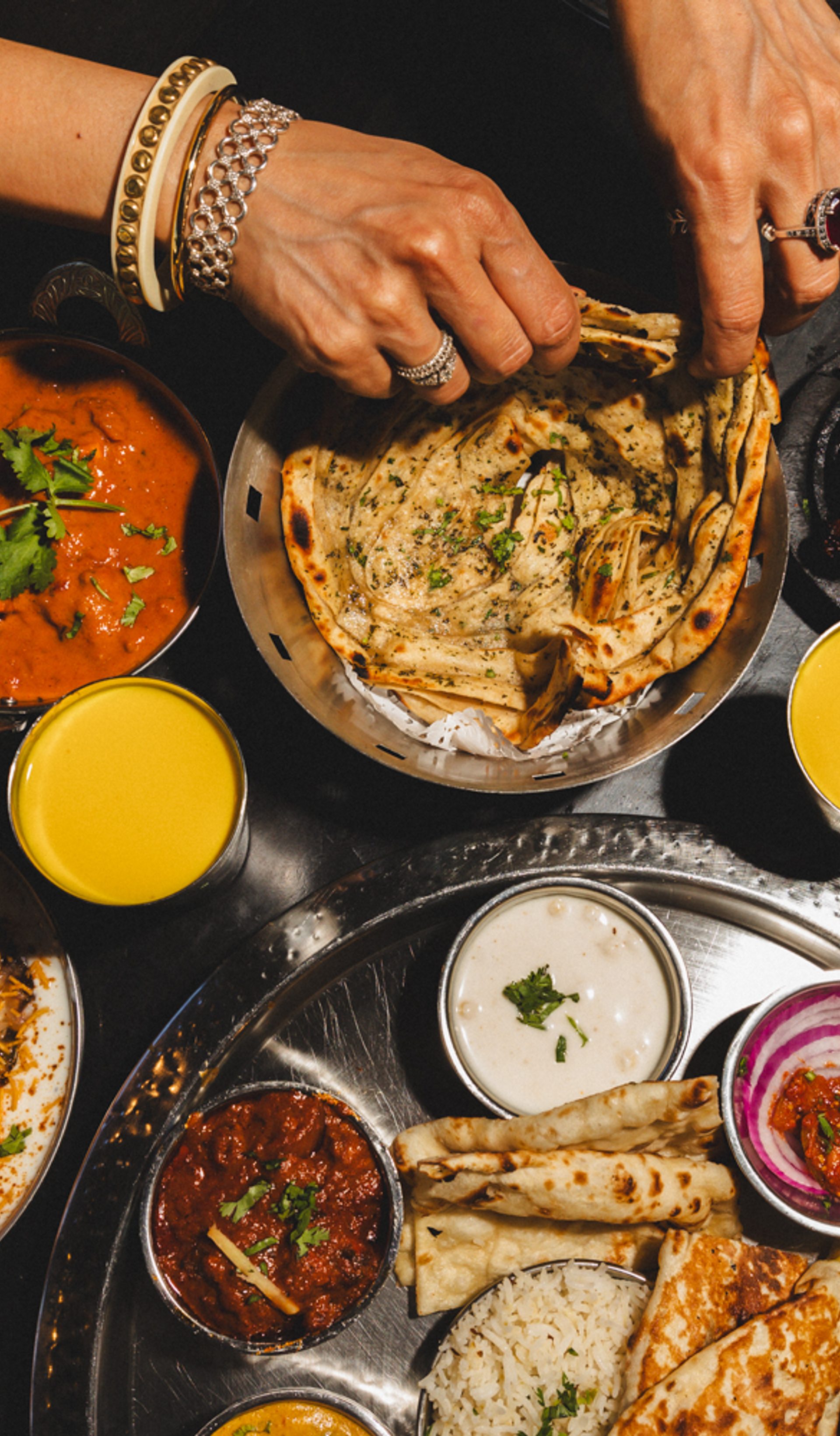 Hands reaching from a feast of food.