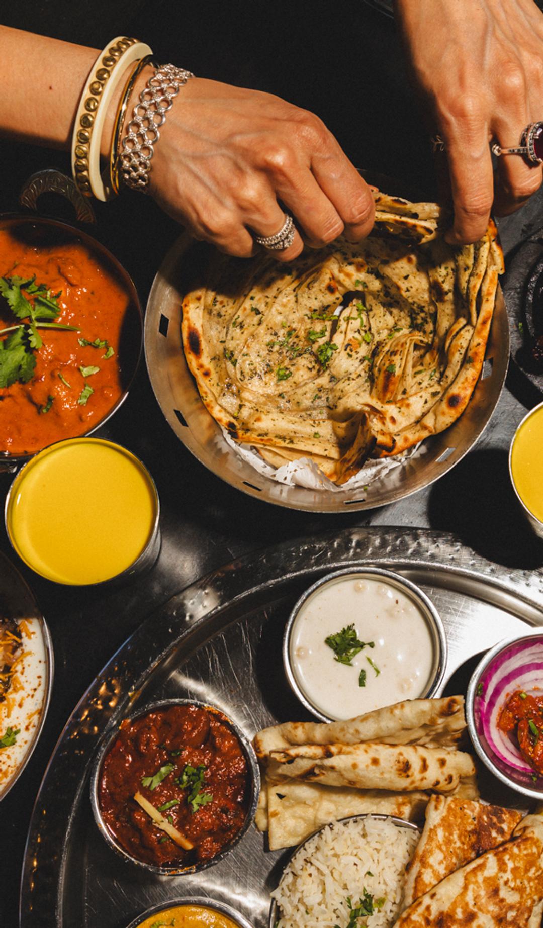 Hands reaching from a feast of food.