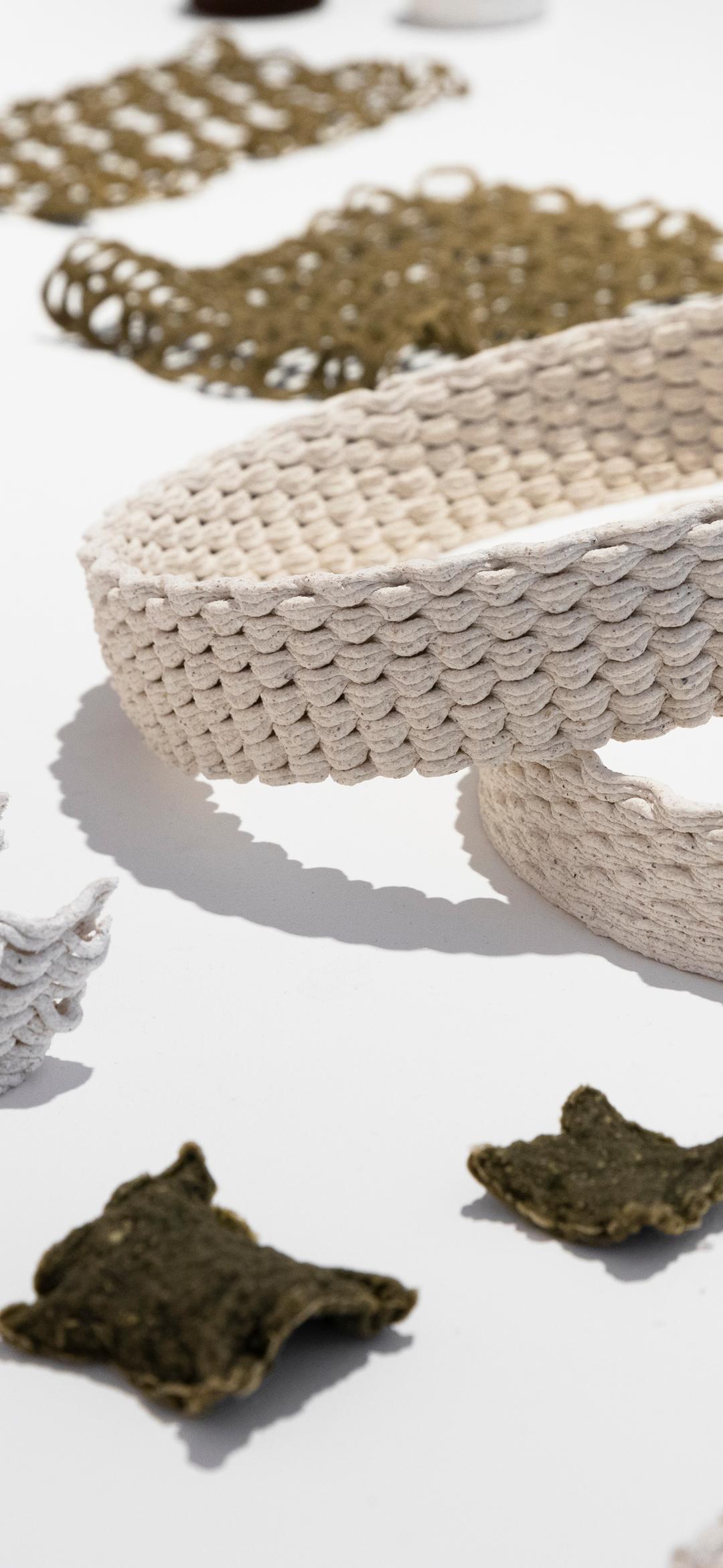 A table of material testing samples including objects 3D printed from algae, oyster shell waste and biobased plastics.