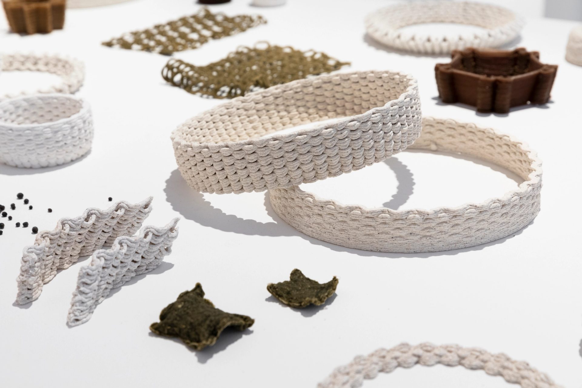 A table of material testing samples including objects 3D printed from algae, oyster shell waste and biobased plastics.