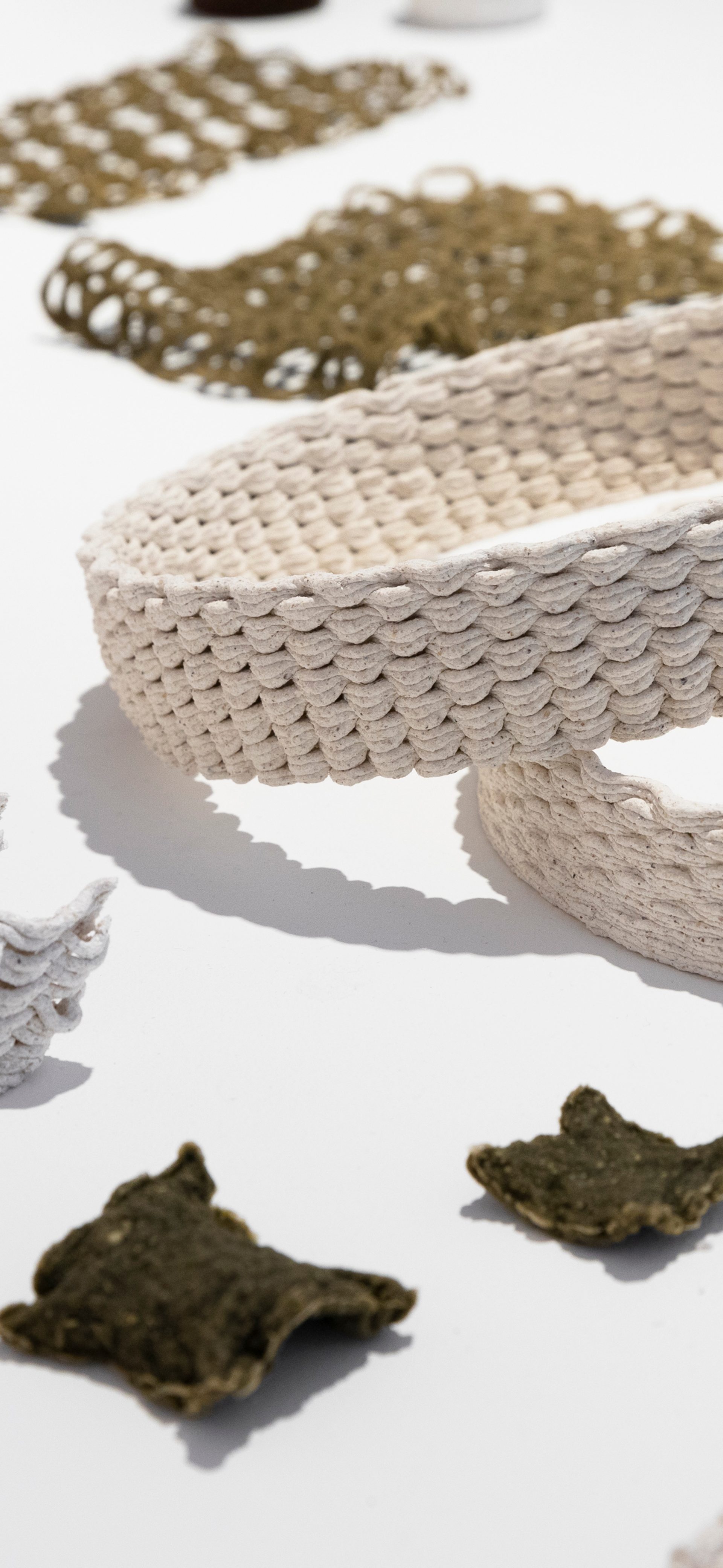 A table of material testing samples including objects 3D printed from algae, oyster shell waste and biobased plastics.