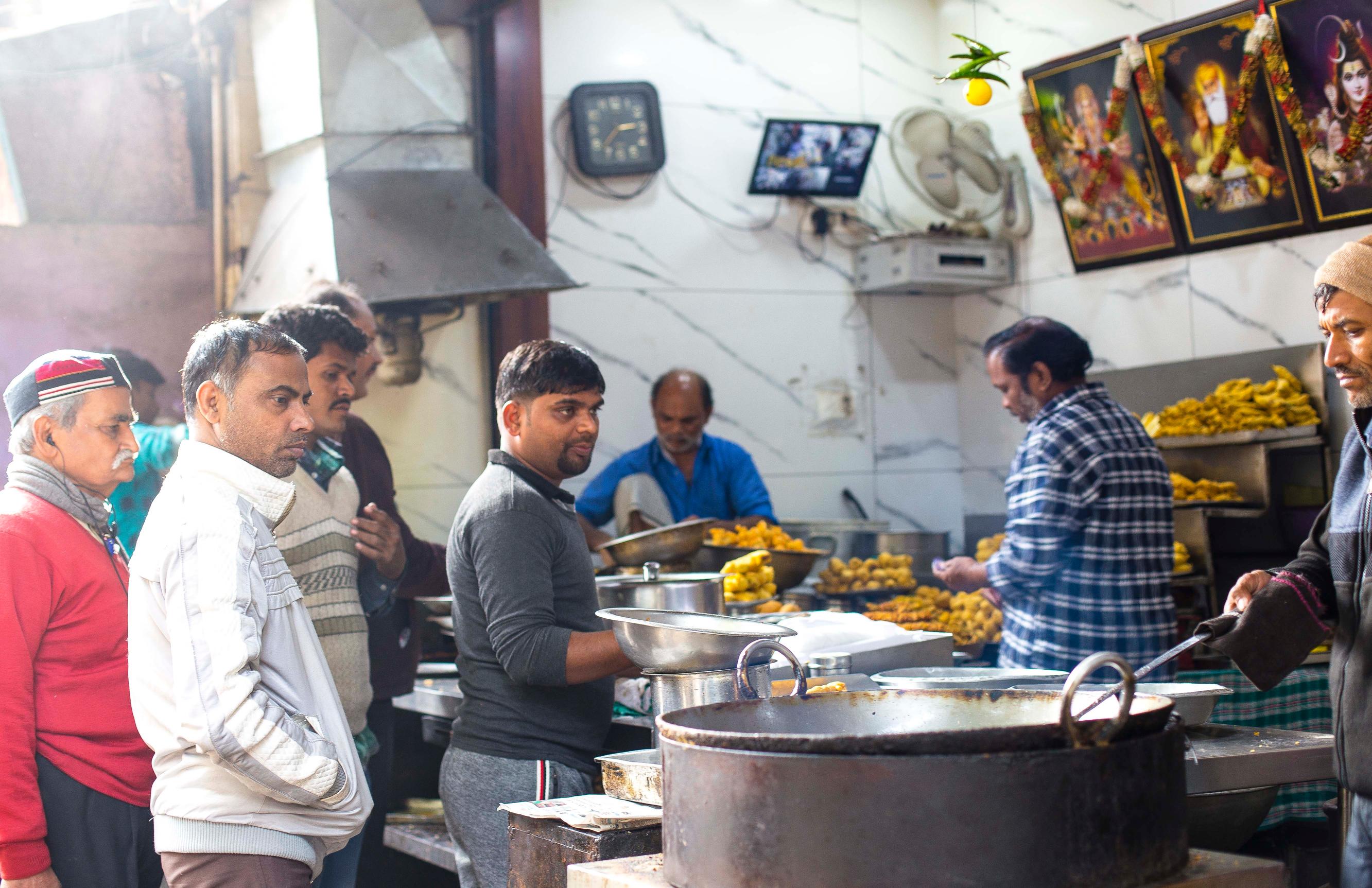 A bustling kitchen scene in an Indian street food stall.