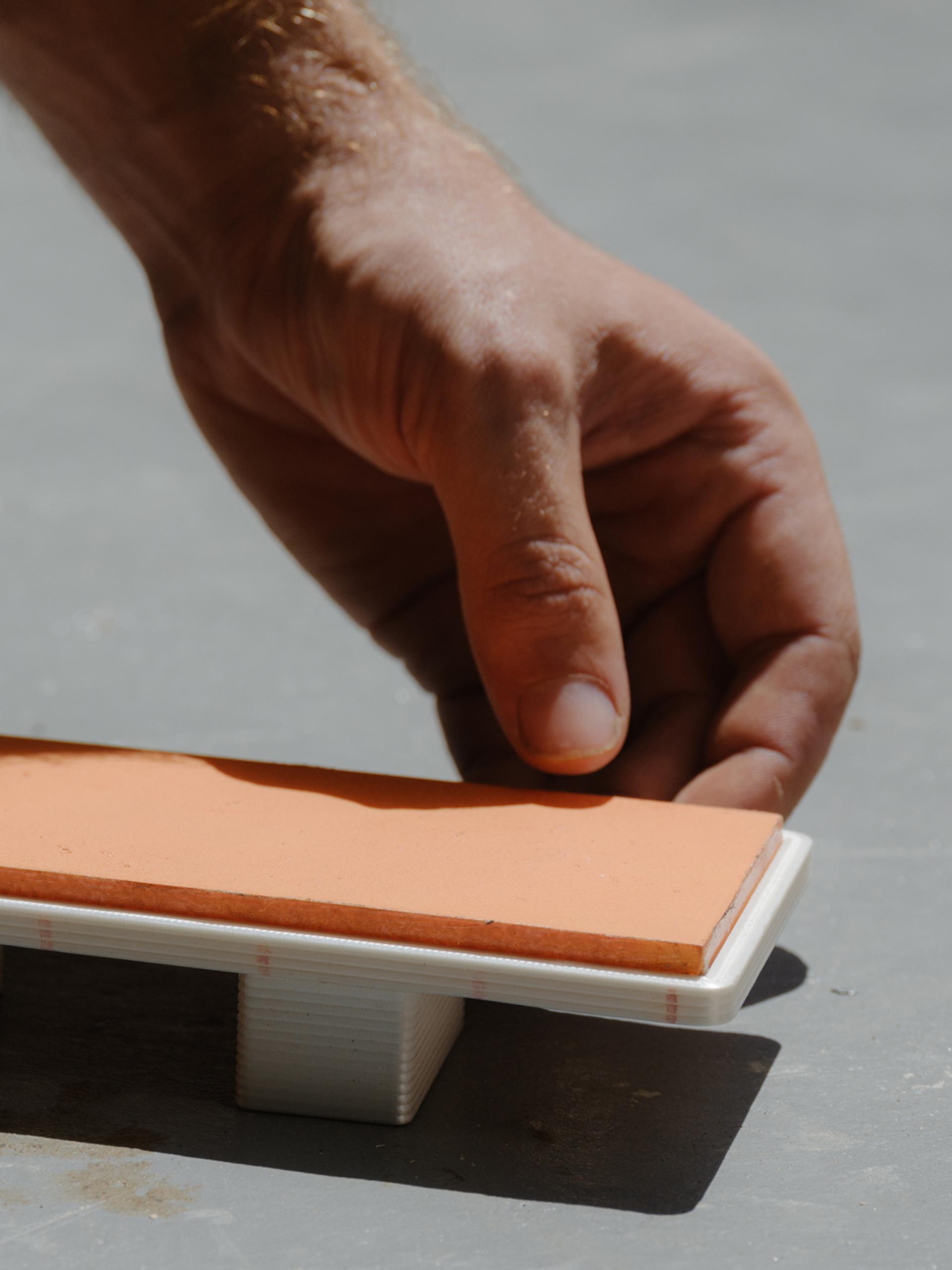 Tiny model of daybed being placed in the sun by two hands.