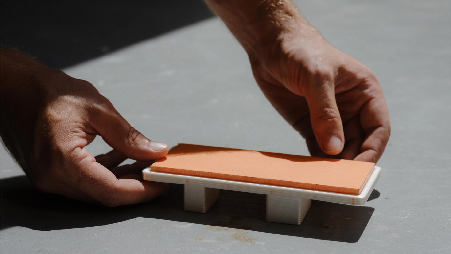 Tiny model of daybed being placed in the sun by two hands.