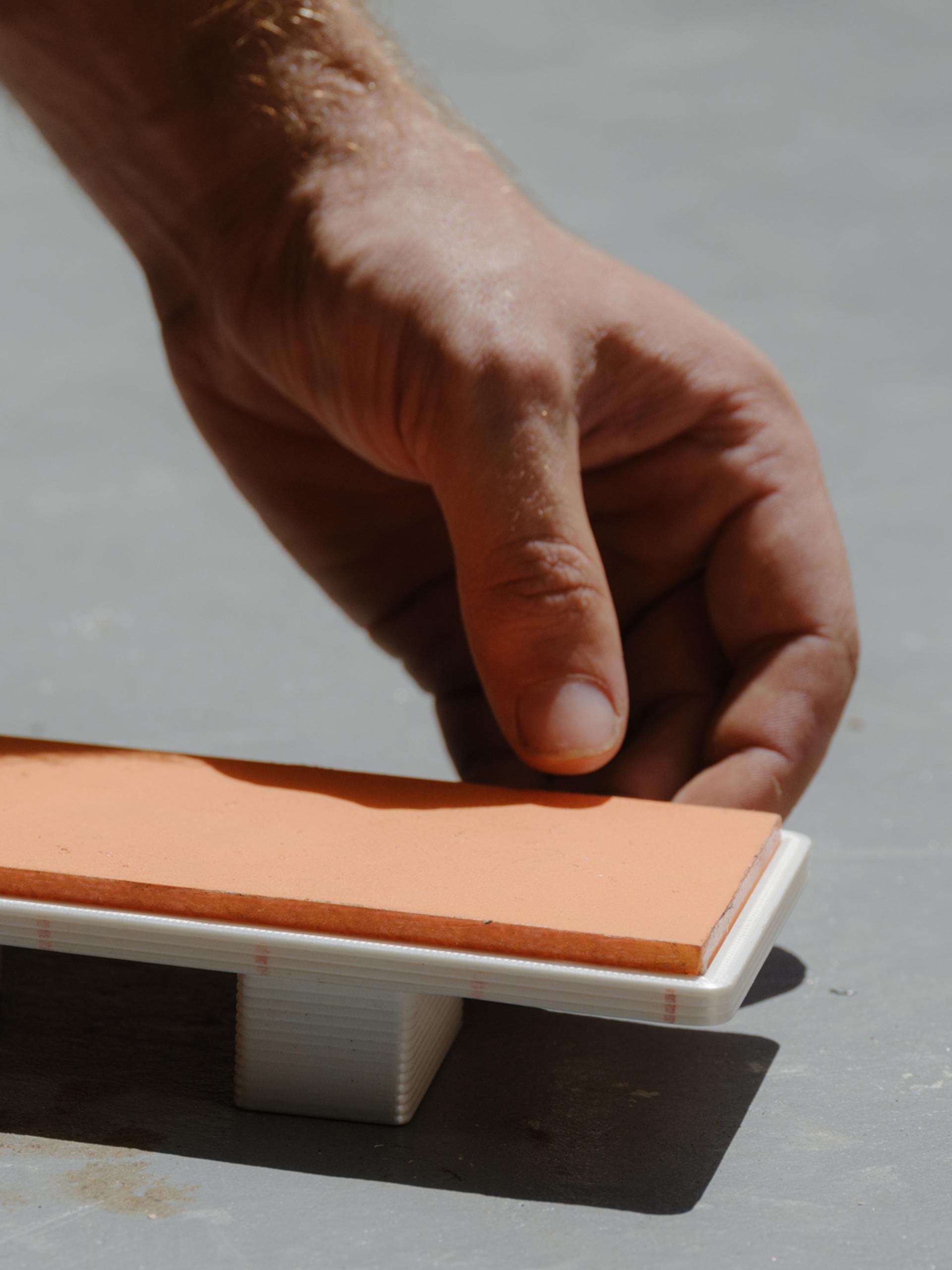 Tiny model of daybed being placed in the sun by two hands.