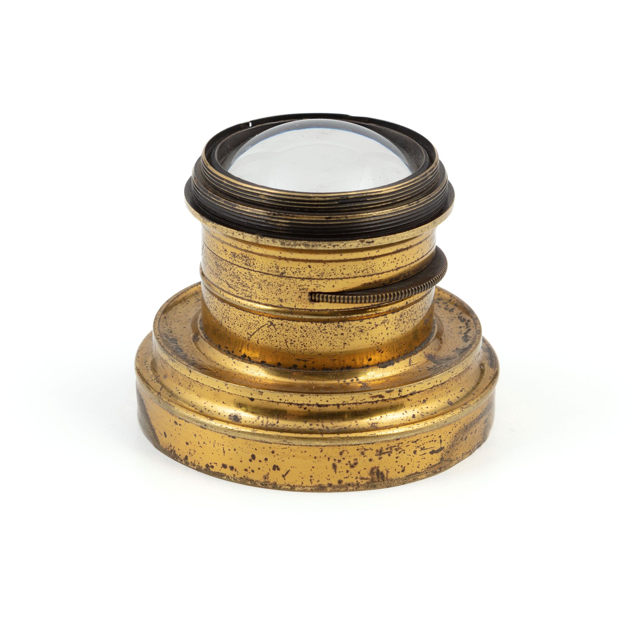 A brass cylinder which is inset a the end with a curved  disc of glass.