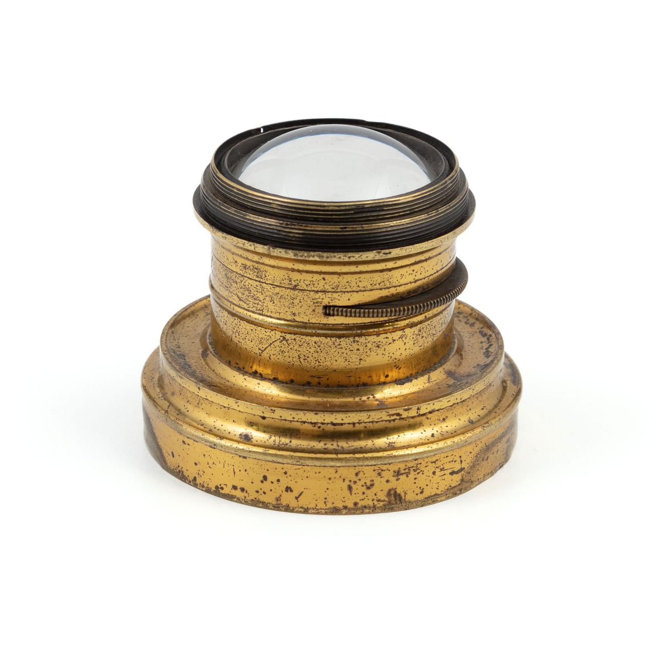 A brass cylinder which is inset a the end with a curved disc of glass.