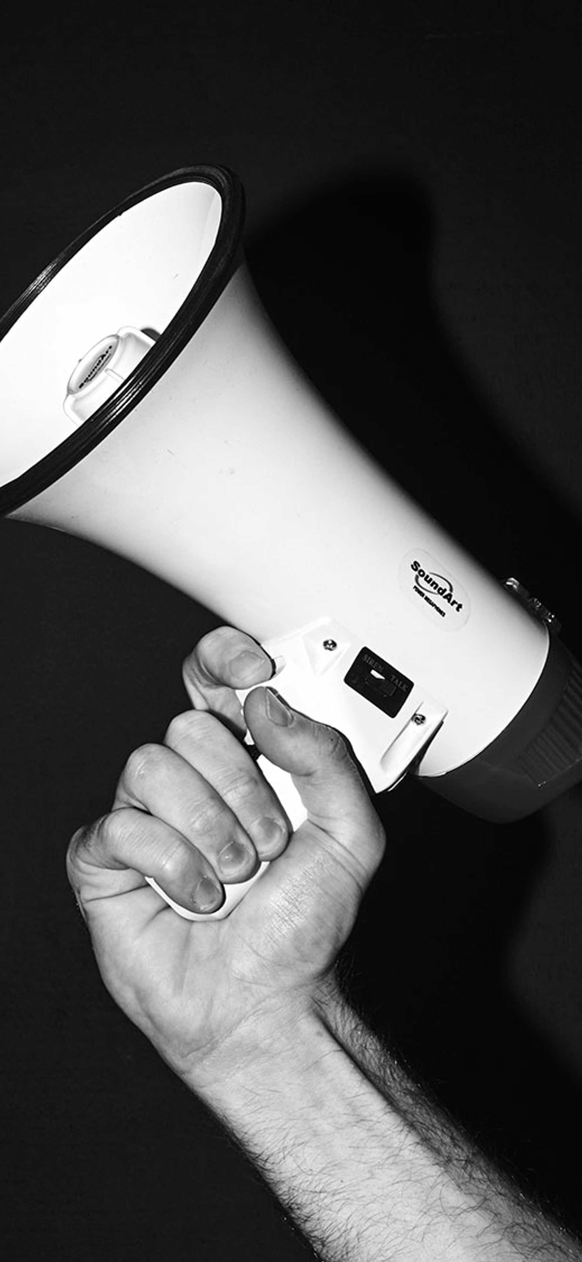 Black and white image of a hand holding a megaphone