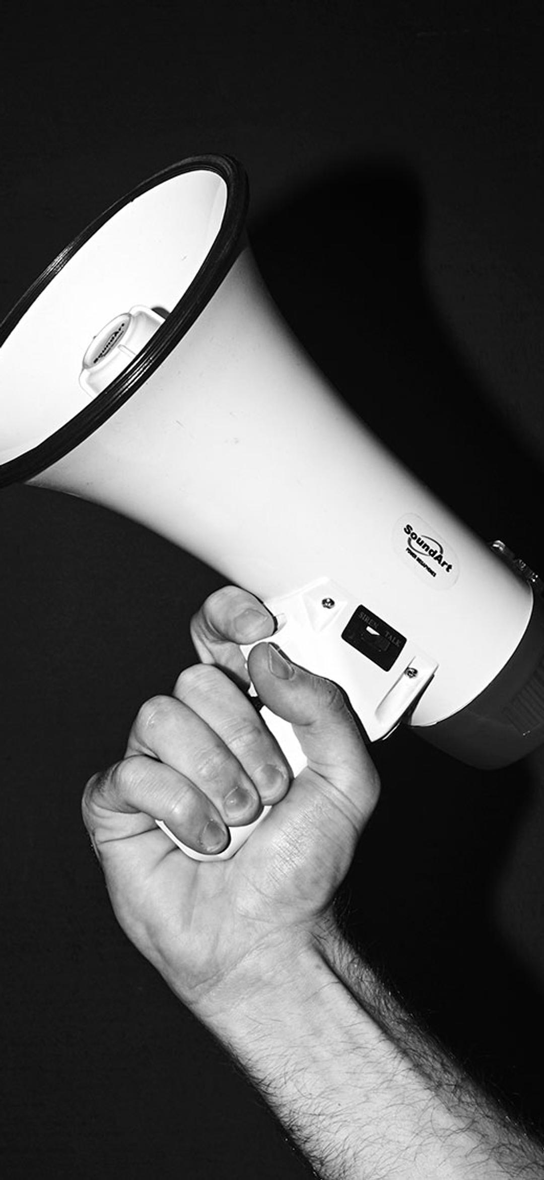 Black and white image of a hand holding a megaphone