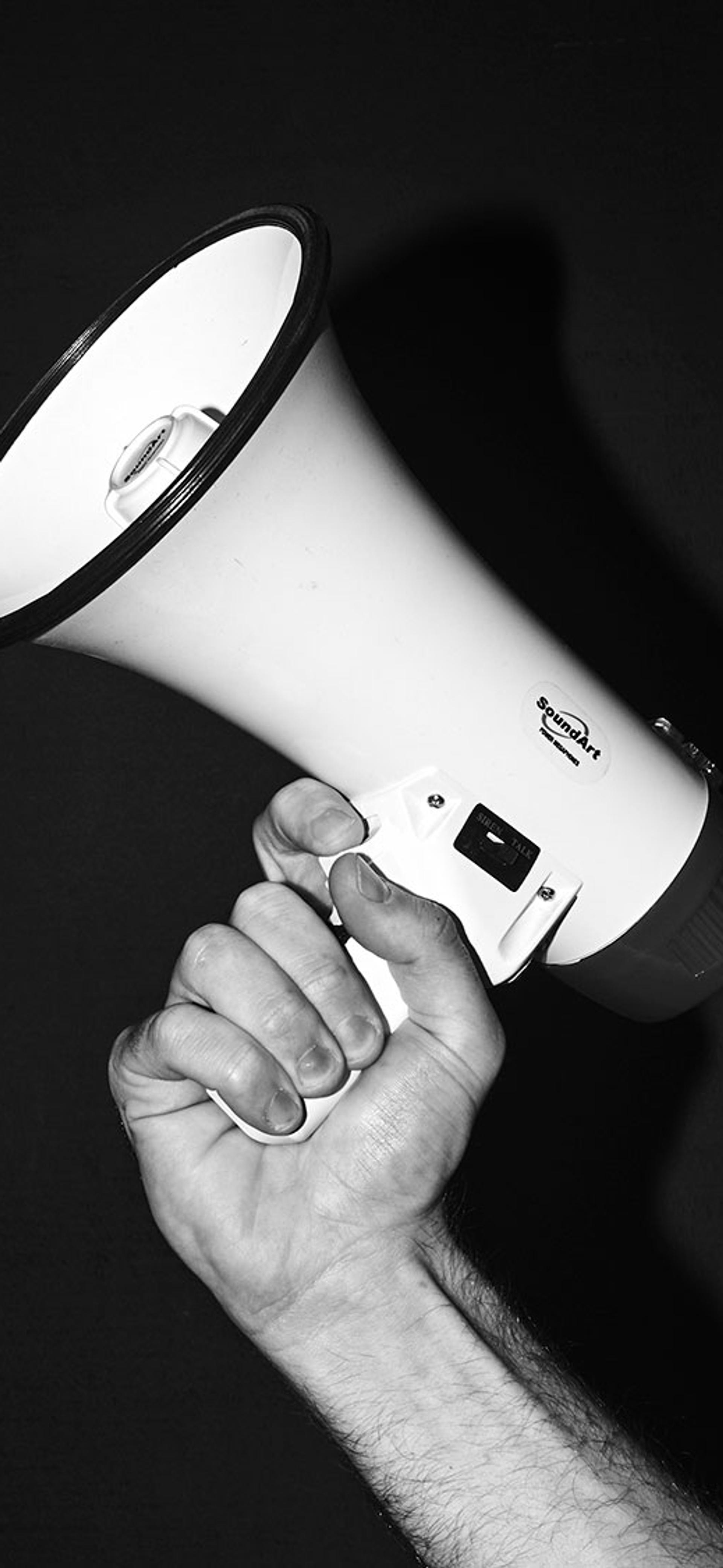 Black and white image of a hand holding a megaphone