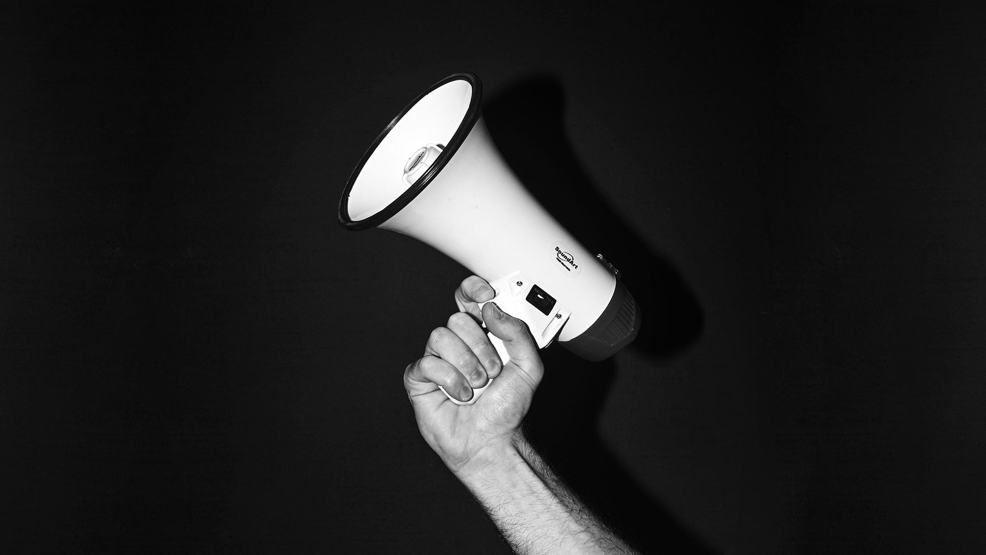 Black and white image of a hand holding a megaphone