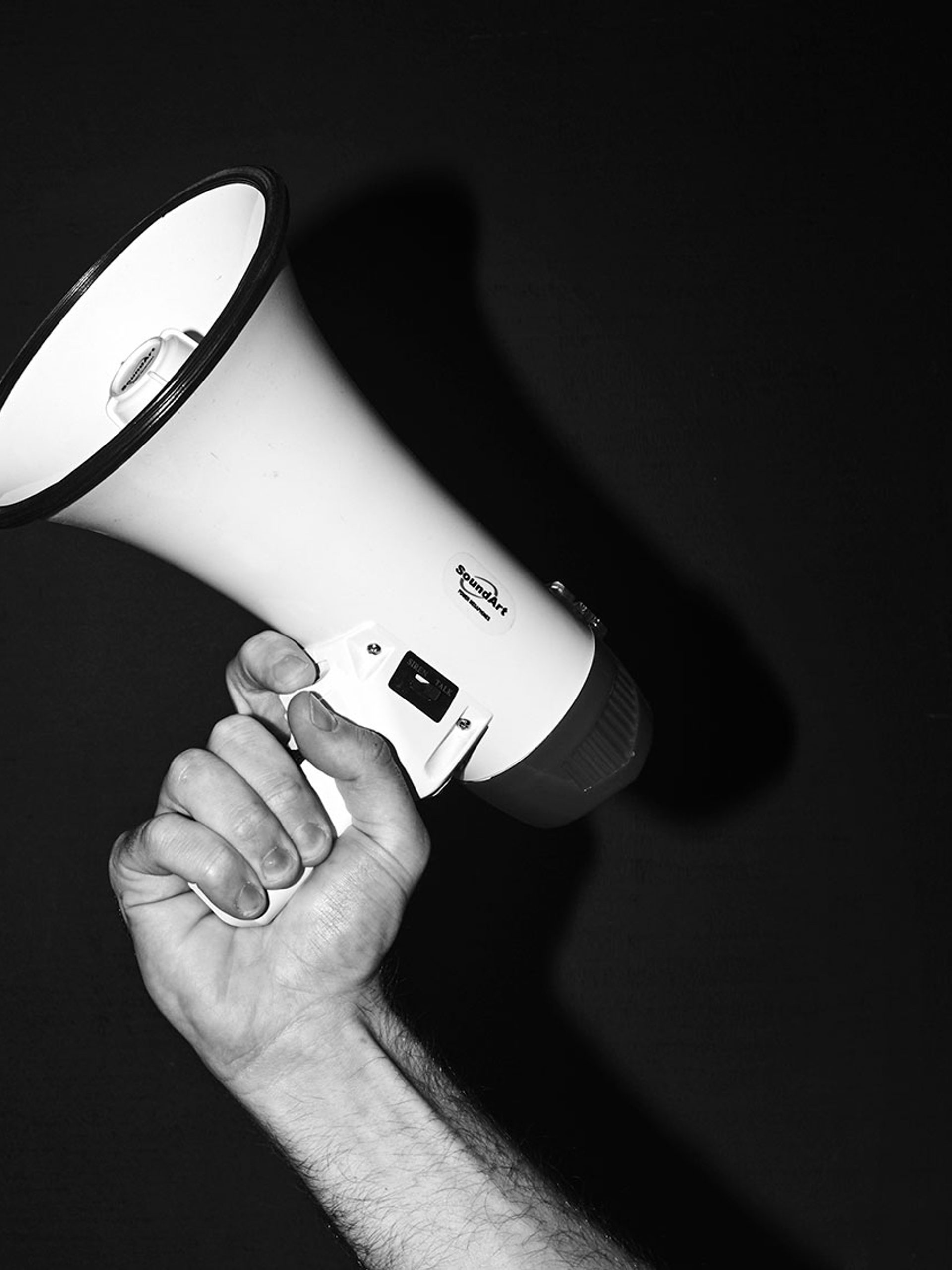 Black and white image of a hand holding a megaphone
