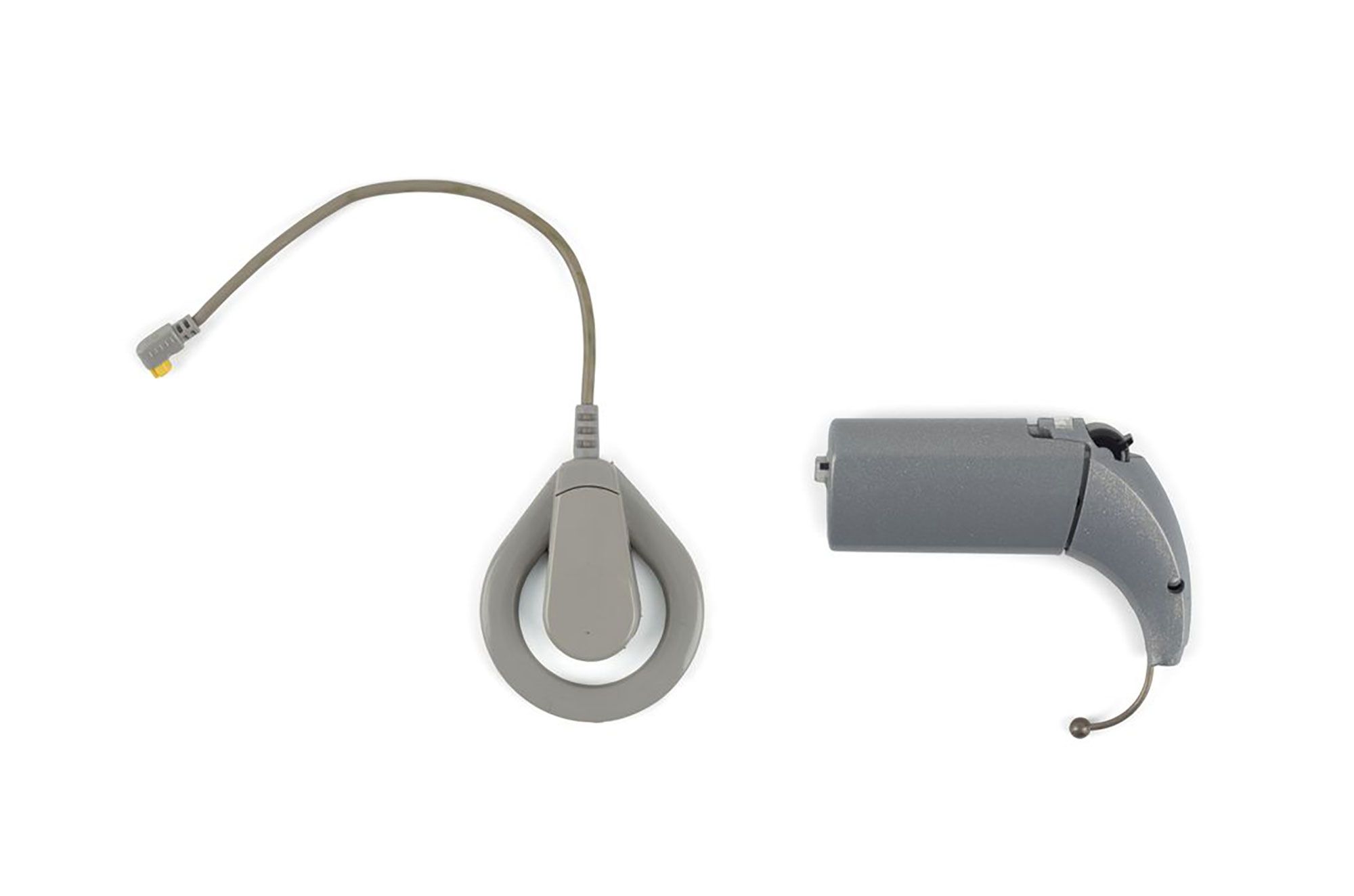 Grey cochlear implant and speech processor photographed against white background