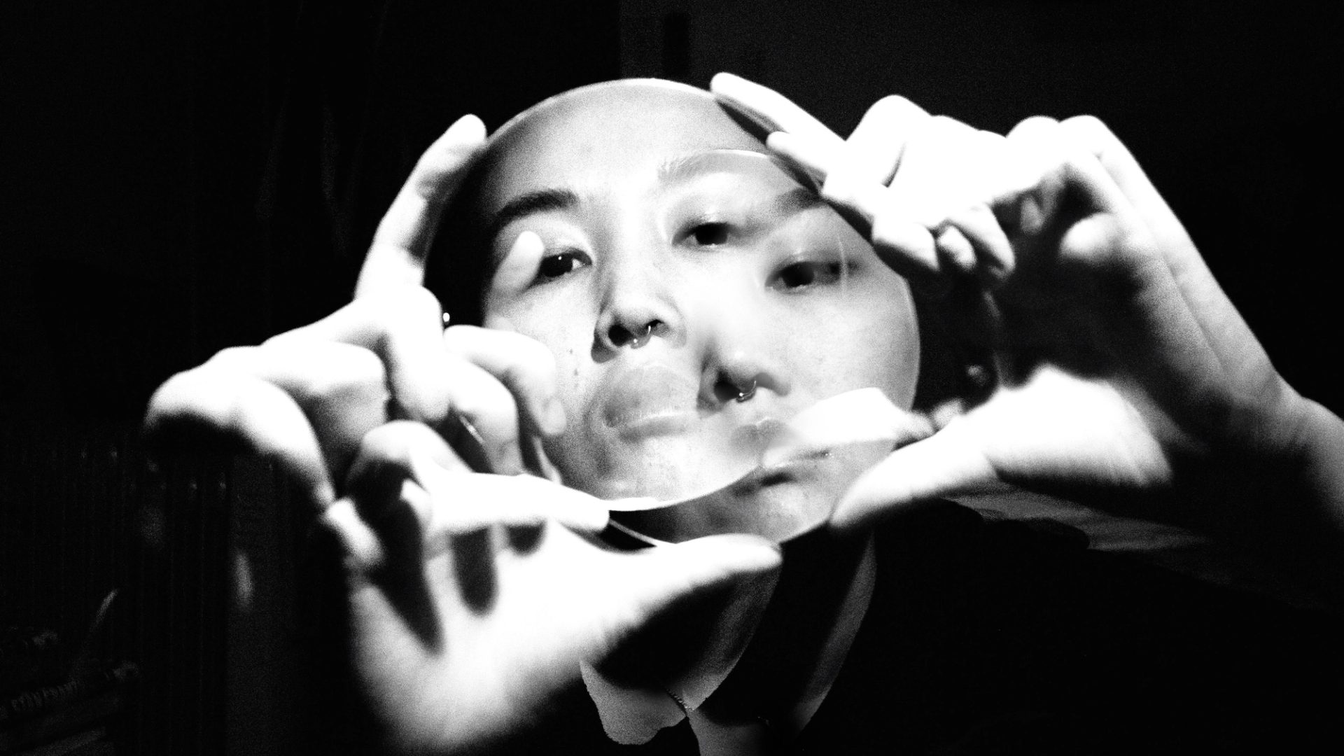 Double exposure photo, of hands holding a clear disk in front of face for framing.