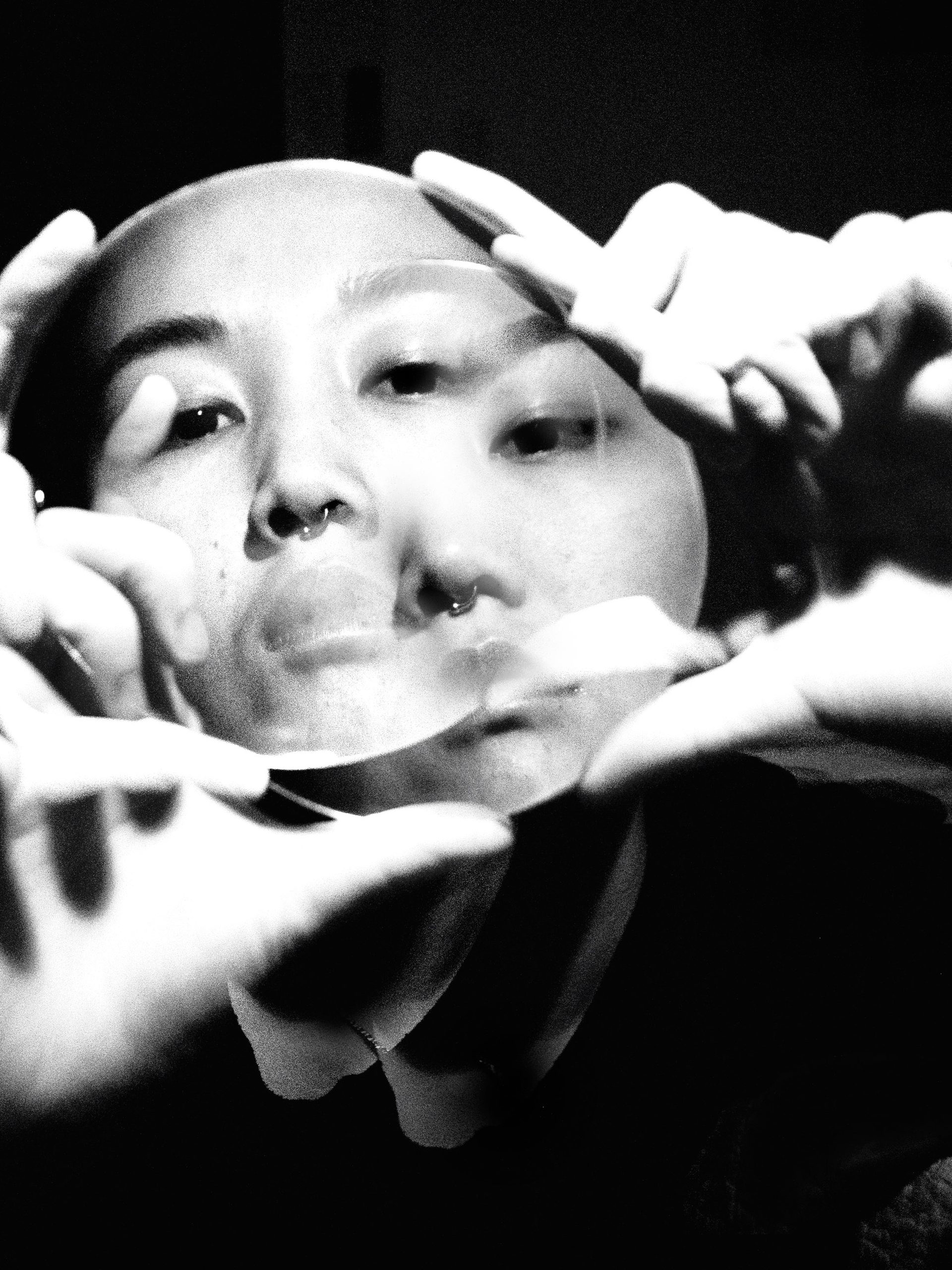 Double exposure photo, of hands holding a clear disk in front of face for framing.