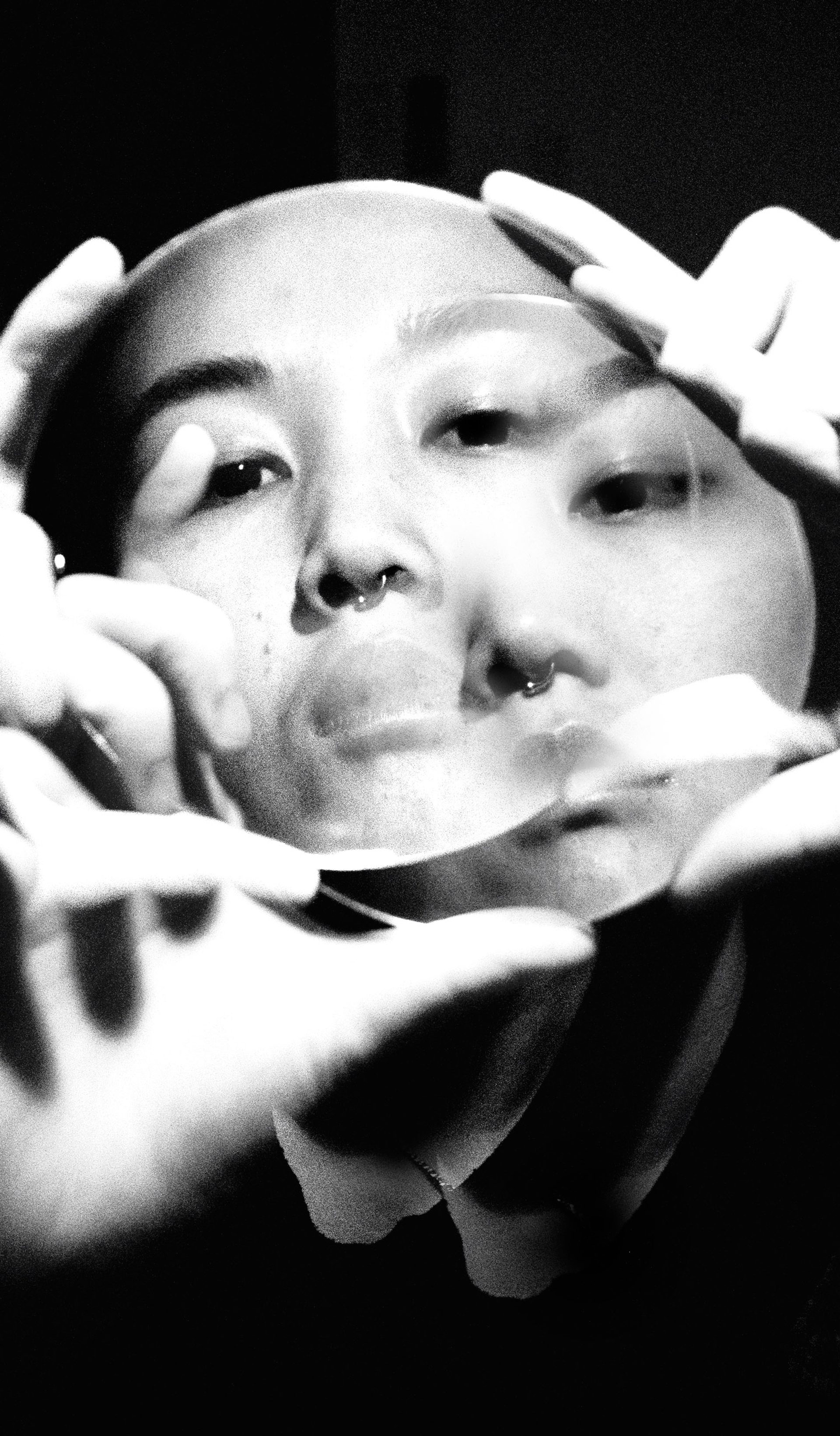 Double exposure photo, of hands holding a clear disk in front of face for framing.