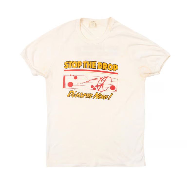 White concert shirt, with yellow text 'Stop the Drop' concert t-shirt.