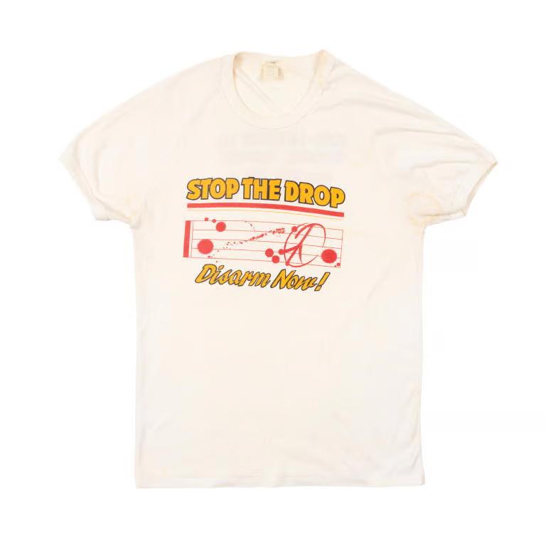 White concert shirt, with yellow text 'Stop the Drop' concert t-shirt.