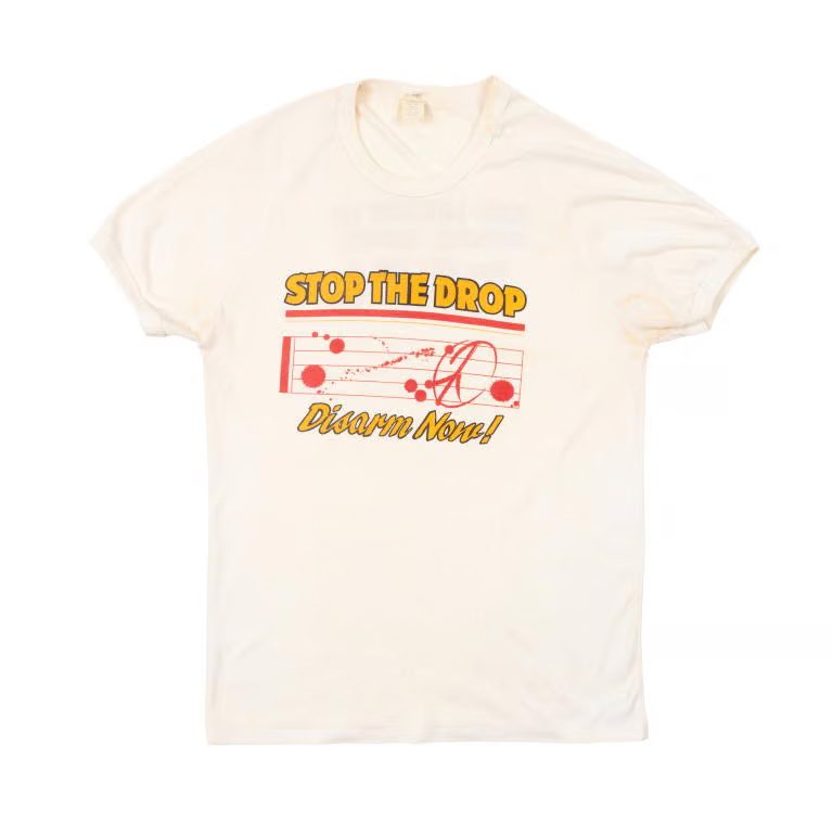White concert shirt, with yellow text 'Stop the Drop' concert t-shirt.