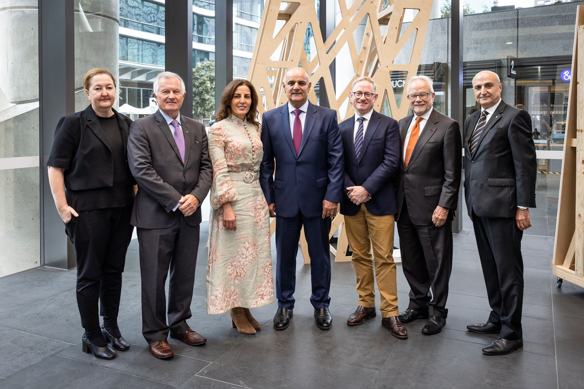 Seven people stand and pose for a photo, they are smiling at the camera