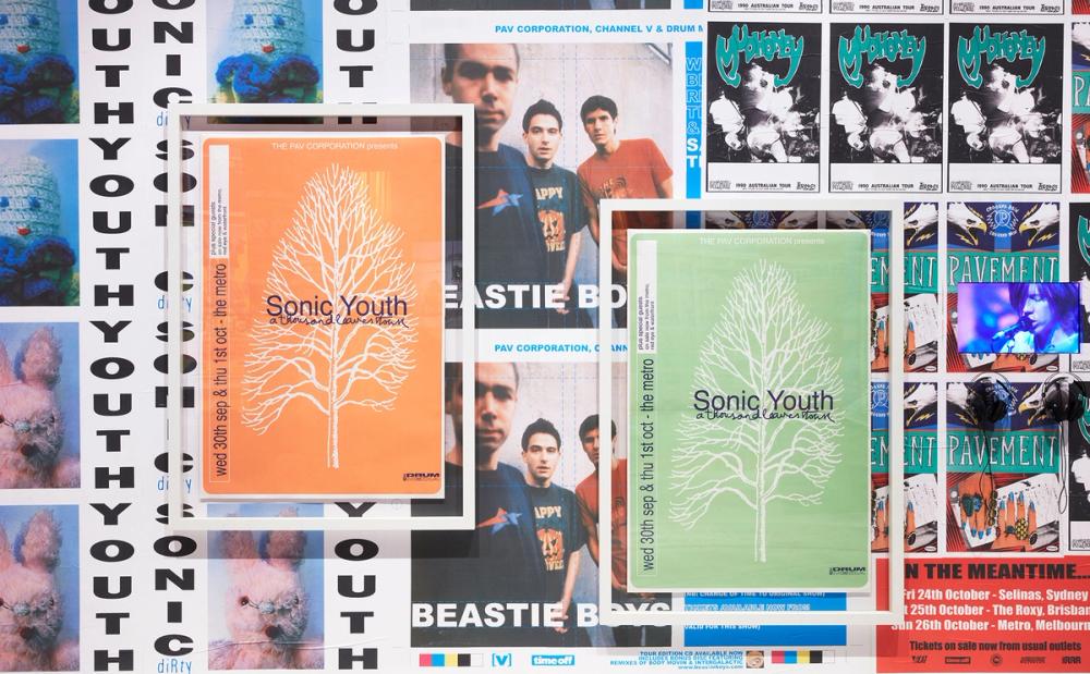 A wall of brightly coloured band posters. In the front are two Sonic Youth posters.