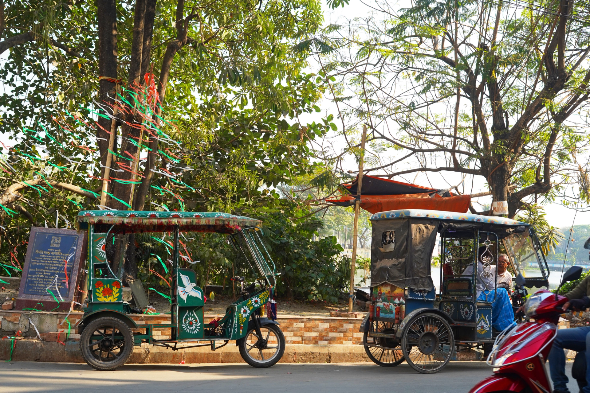 Two electric rickshaws parked on a busy South Asian street.
