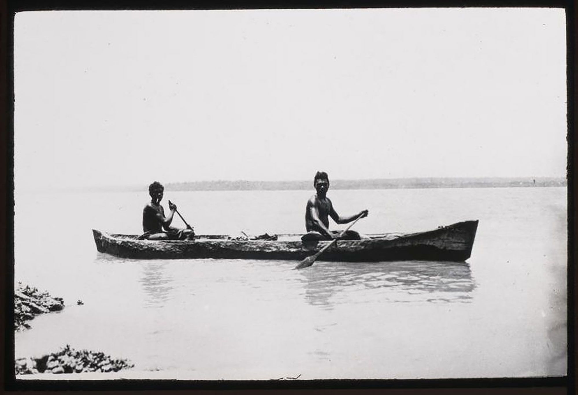 A black and white photograph of two Indigenous men in a canoe, possibly on a lake or the sea.