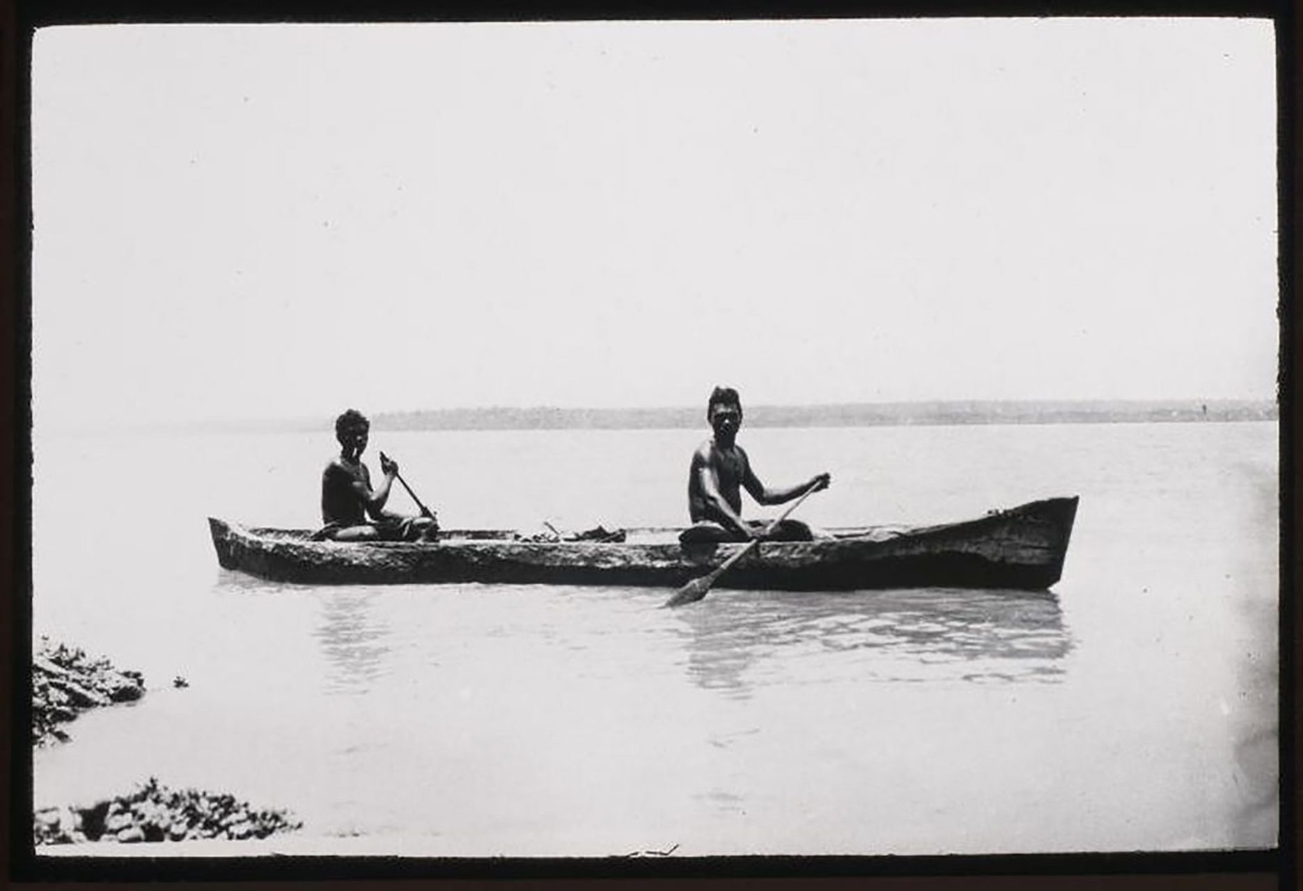 A black and white photograph of two Indigenous men in a canoe, possibly on a lake or the sea.