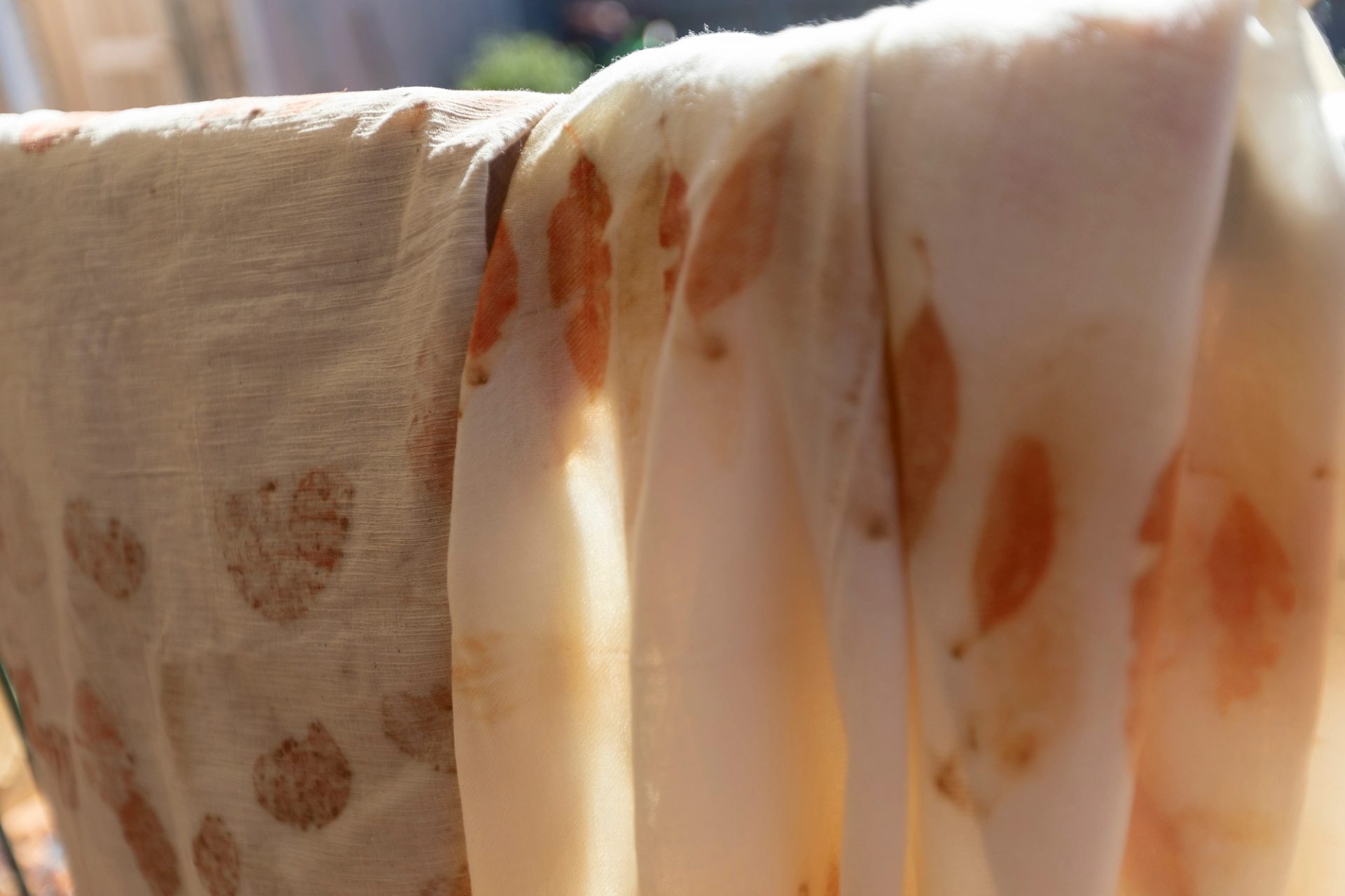 A closeup photograph of textiles printed with an orange eucalyptus leaf pattern.