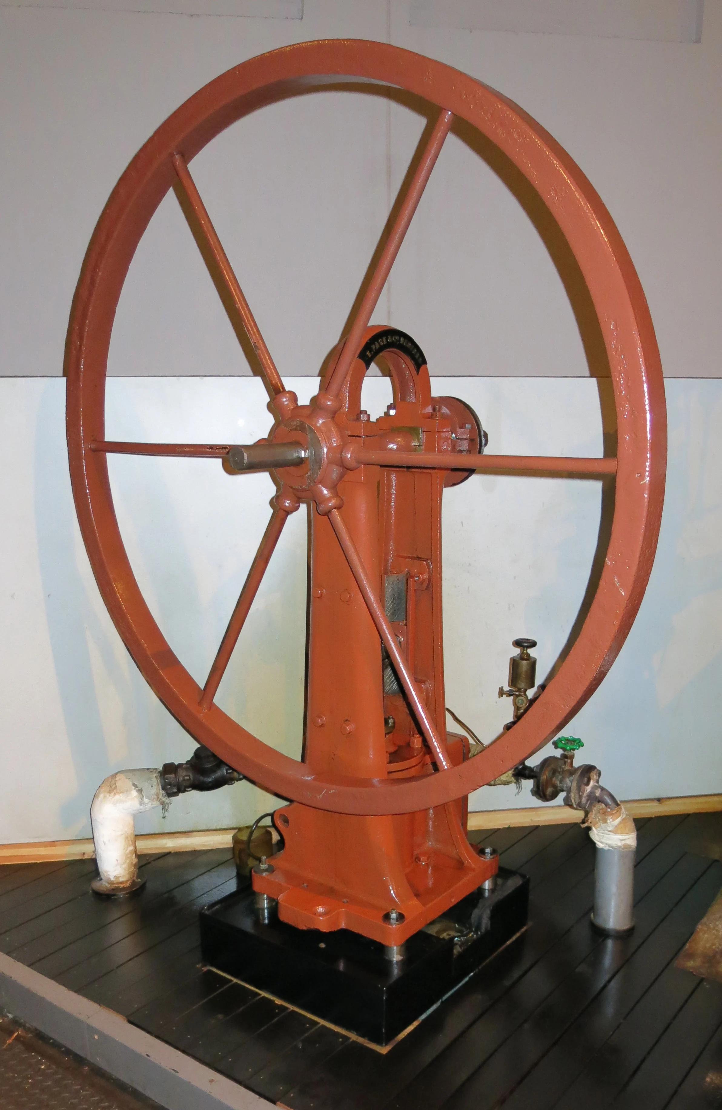 Large red wheel connected to pipes in the ground