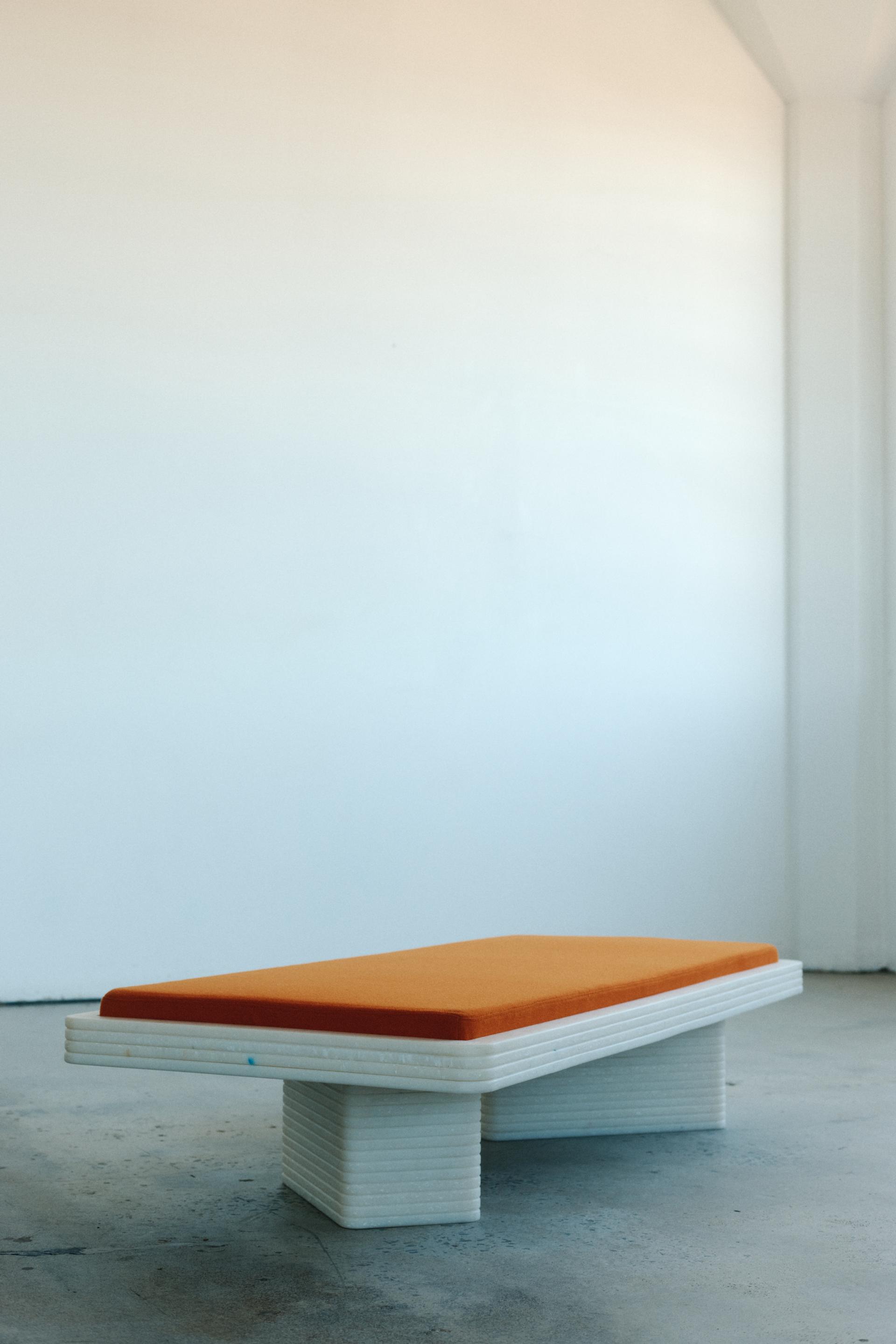 White frame table with large orange cushion atop