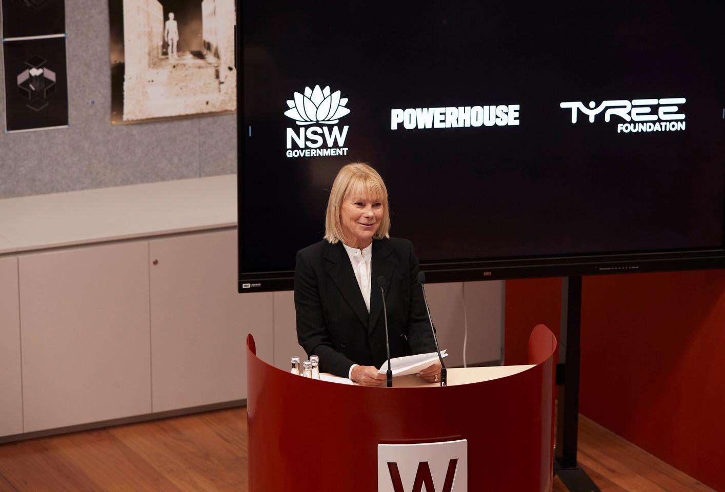 Woman stands at podium with speech notes