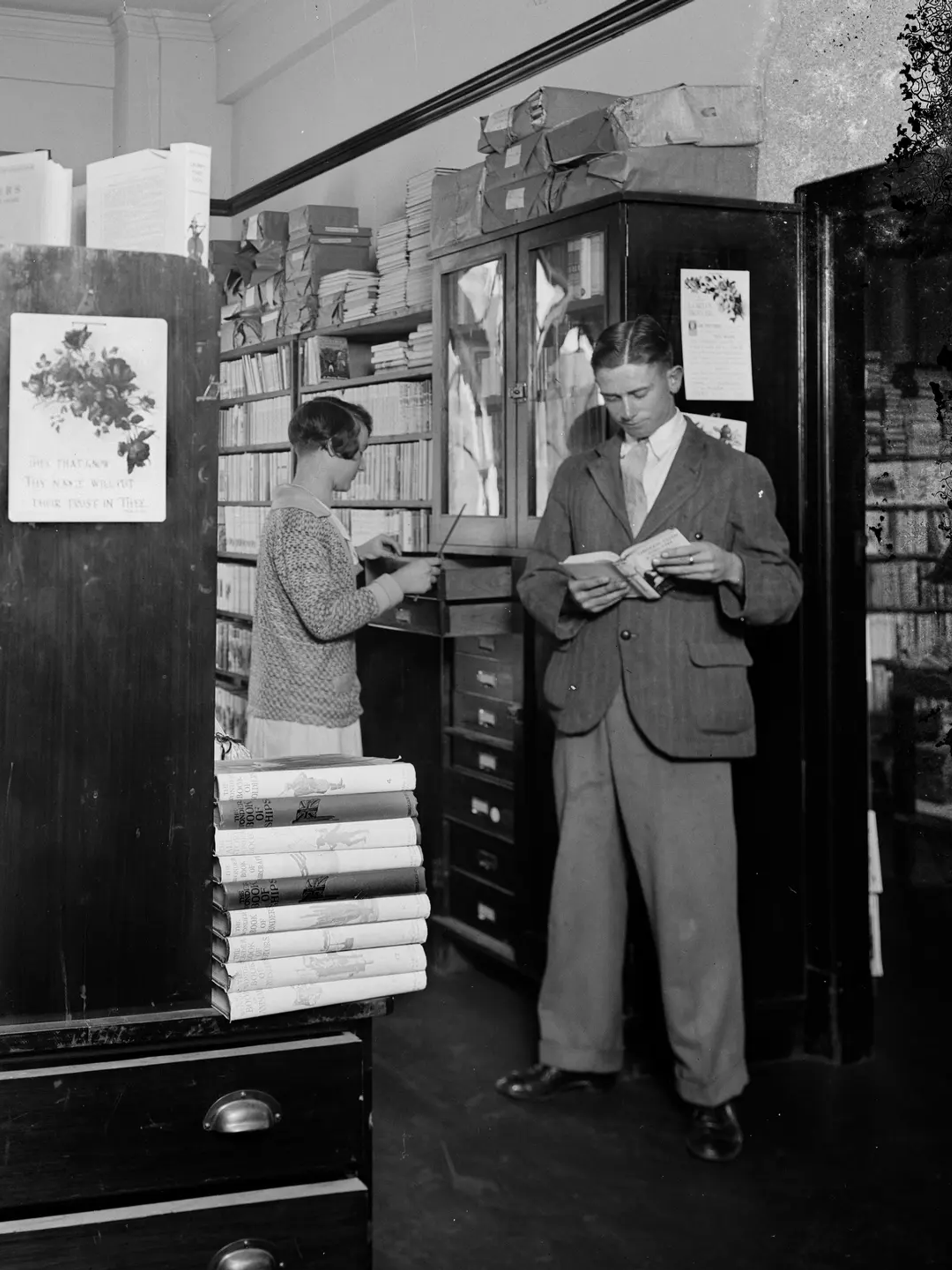 A landscape black and white photograph depicting two men and two women browsing in the book room, later known as the Margaret Street Bookshop.