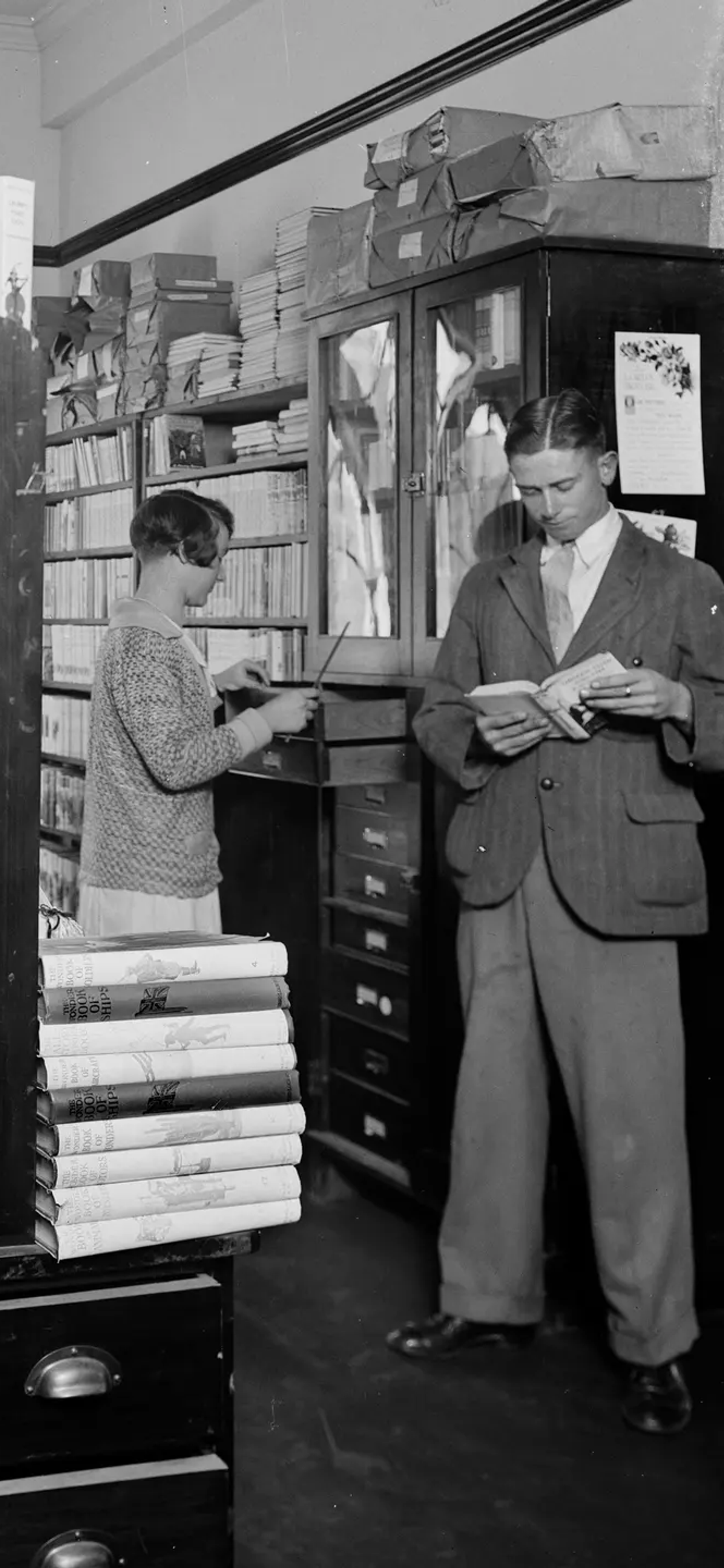 A landscape black and white photograph depicting two men and two women browsing in the book room, later known as the Margaret Street Bookshop.