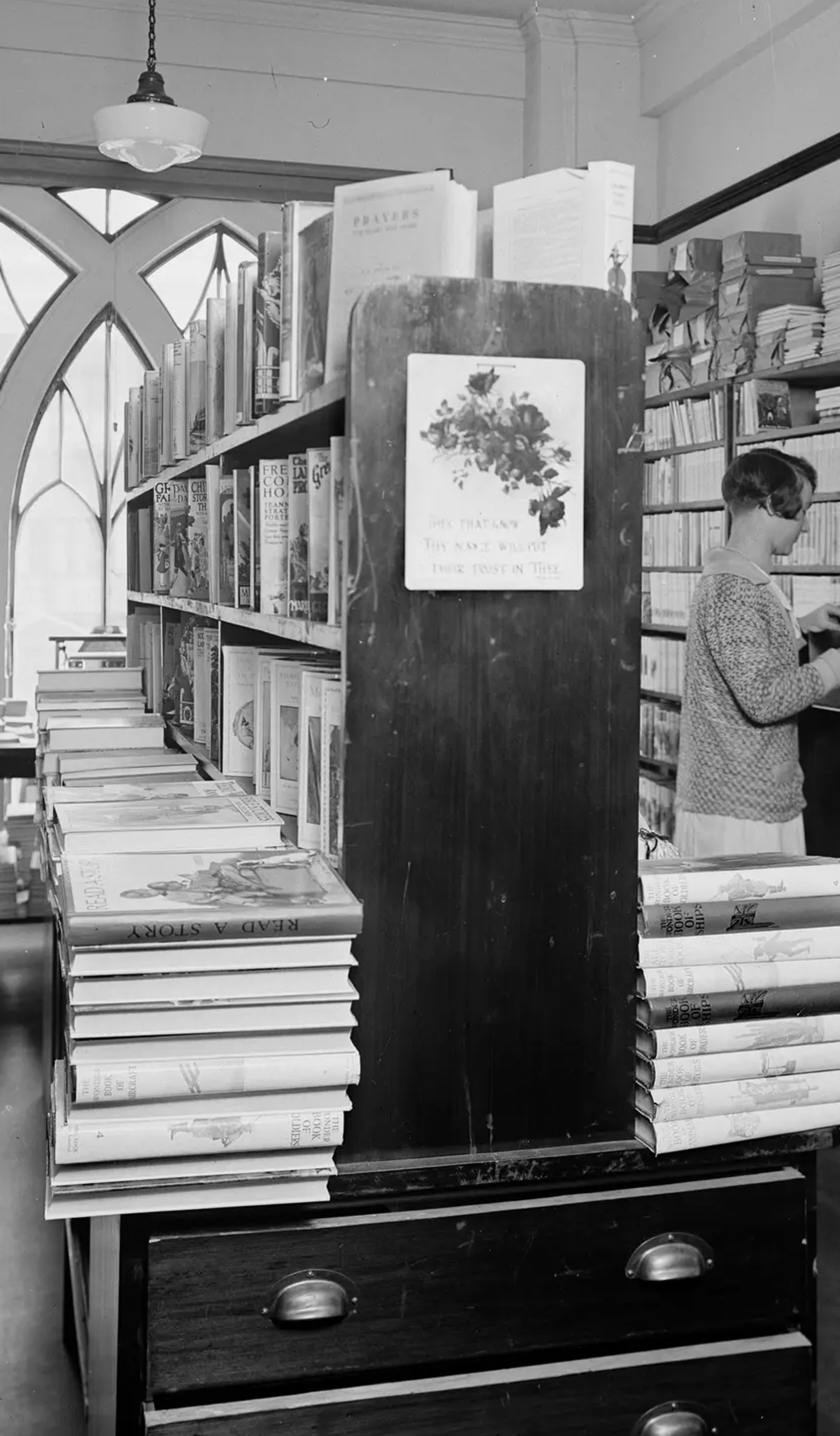 A landscape black and white photograph depicting two men and two women browsing in the book room, later known as the Margaret Street Bookshop.