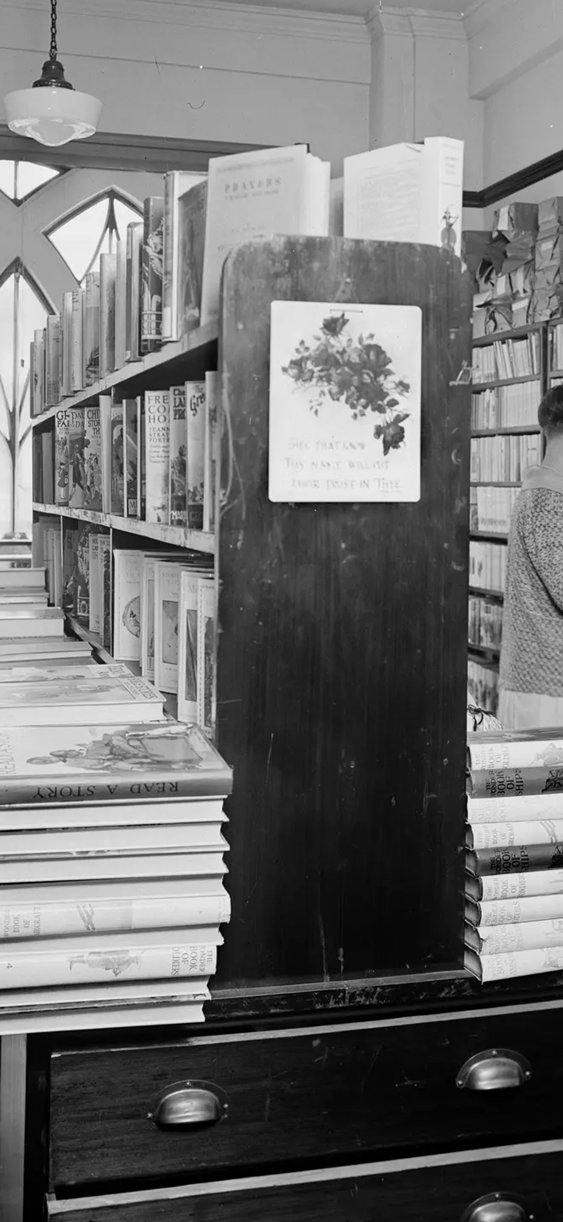A landscape black and white photograph depicting two men and two women browsing in the book room, later known as the Margaret Street Bookshop.