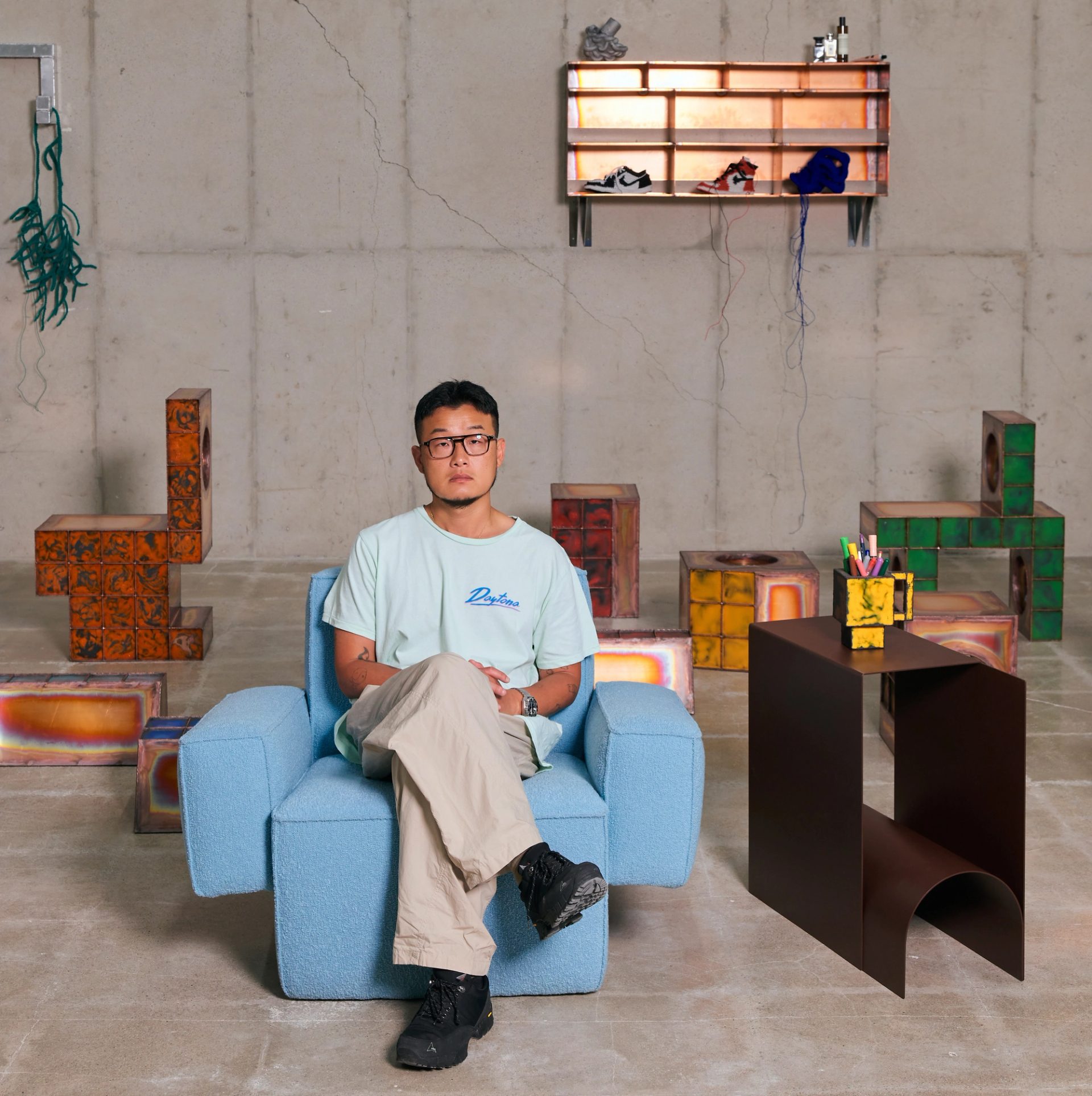 Casually dressed man sits amongst creative pieces.