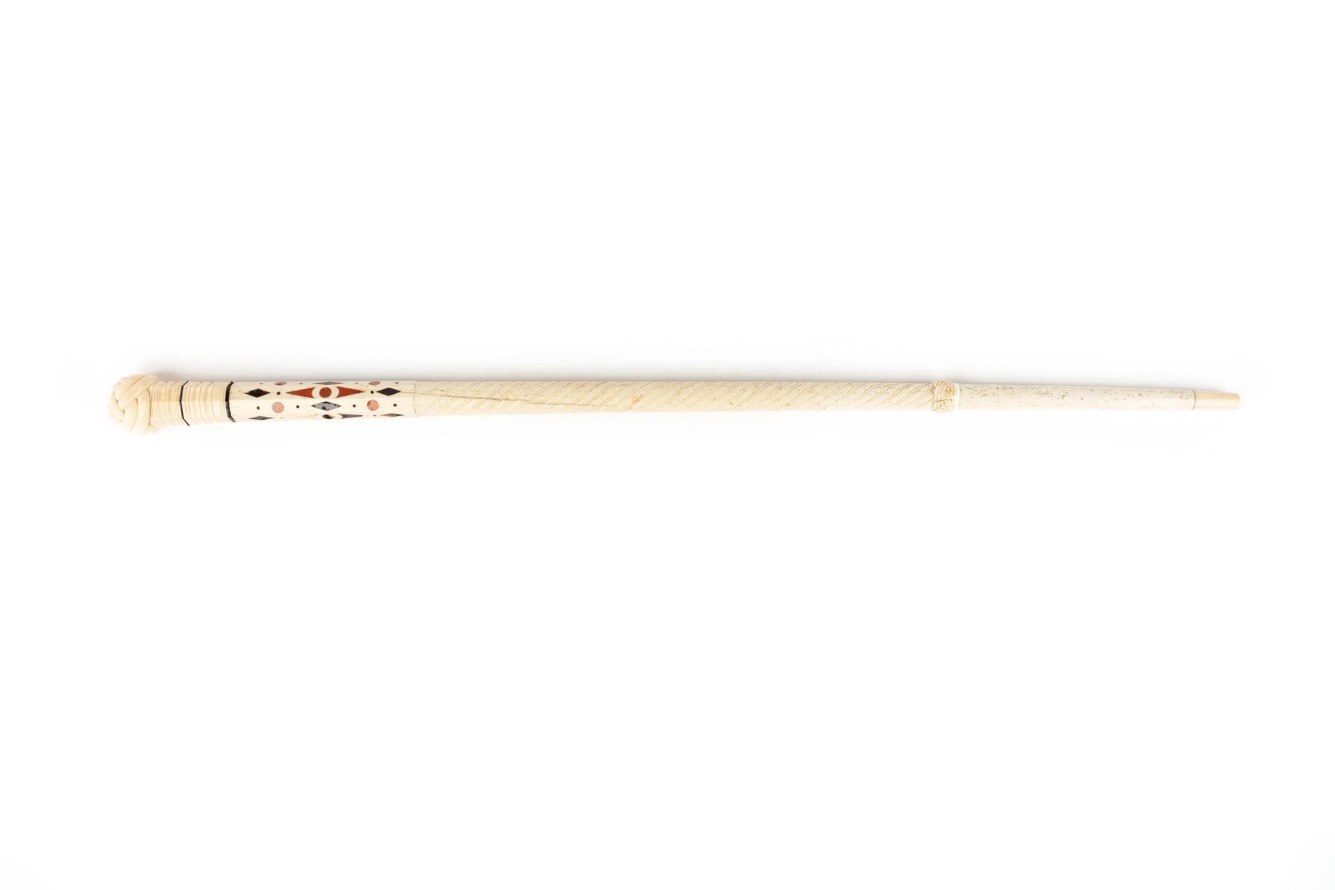 Sperm whale tooth walking stick, with colour and detailed geometrical shapes at the handle.